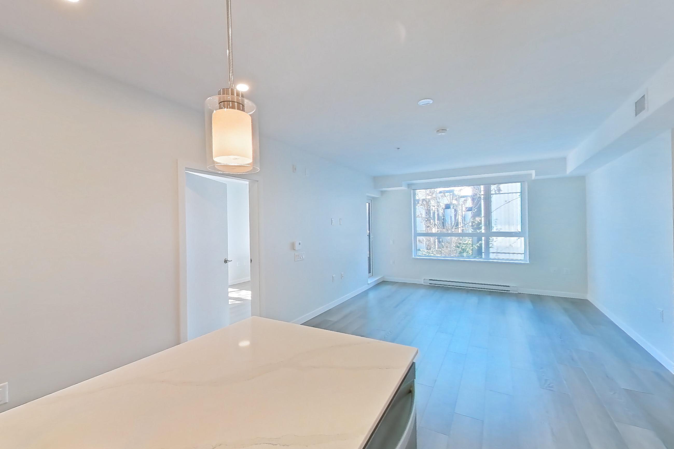 Kitchen with baseboard heating, black appliances, cooktop, dishwasher, electric cooktop, kitchen island, light stone countertops, light wood-finish flooring, oven/range, and stainless steel appliances, Apartment A-205 at Hendry Place