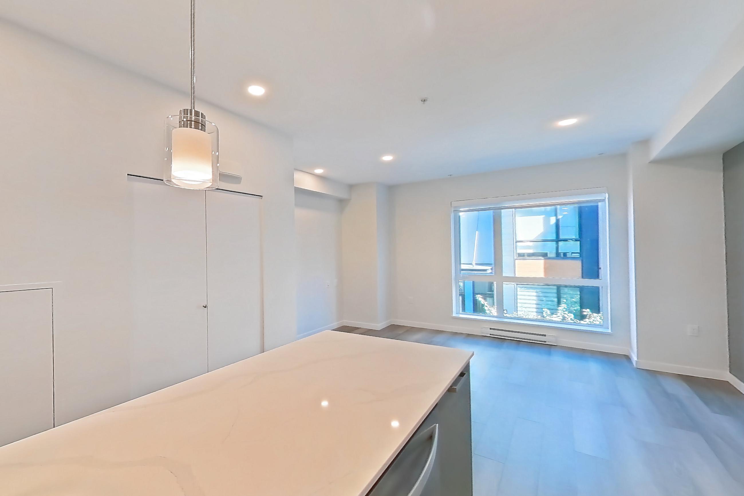 Kitchen with baseboard heating, black appliances, cooktop, dishwasher, electric cooktop, light countertops, light stone countertops, light wood-finish flooring, oven/range, refrigerator, and stainless steel appliances, Apartment T-074 at Hendry Place