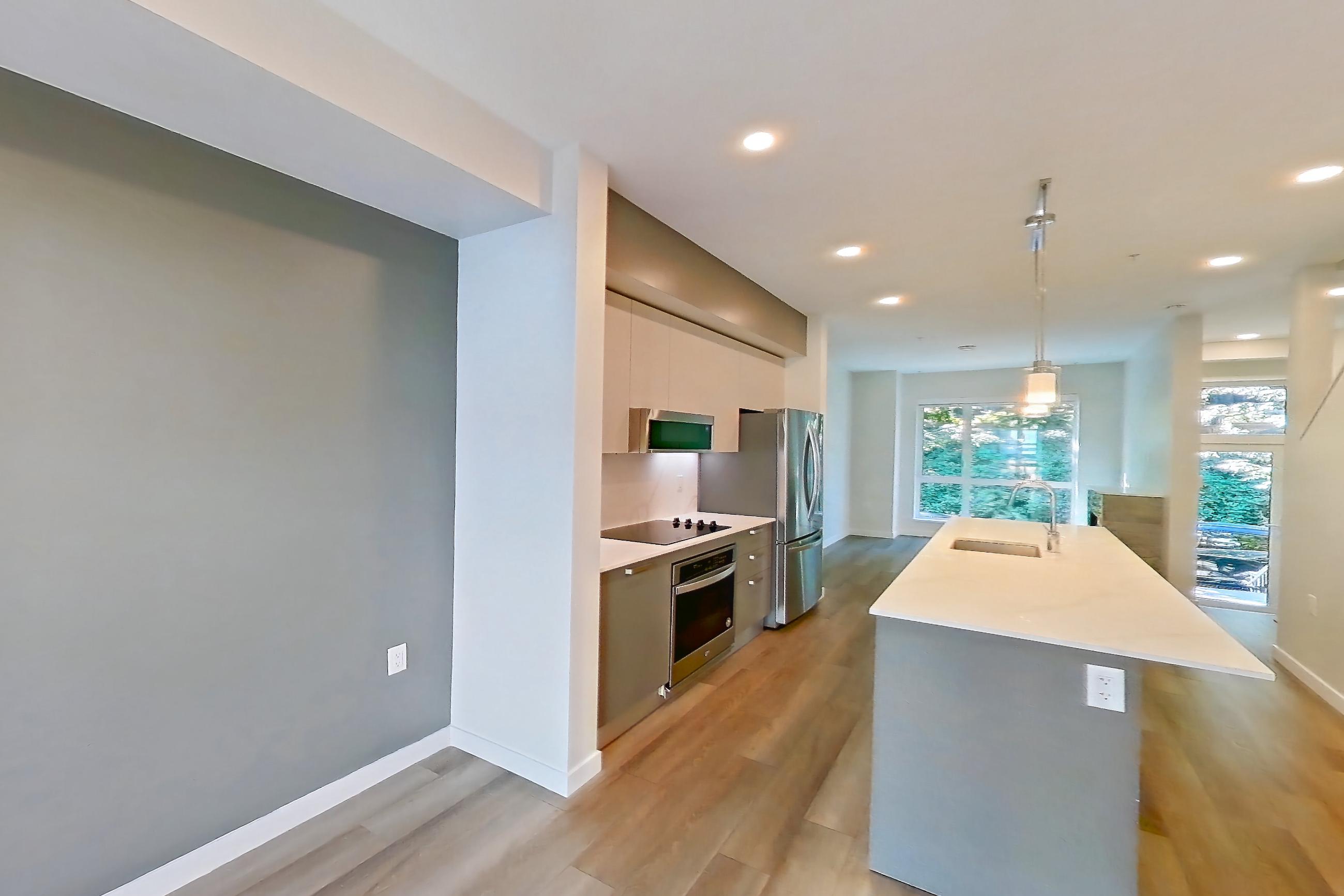 Living room with baseboard heating, black appliances, cooktop, electric cooktop, kitchen island, light stone countertops, light wood-finish flooring, oven/range, refrigerator, and stainless steel appliances, Apartment T-074 at Hendry Place
