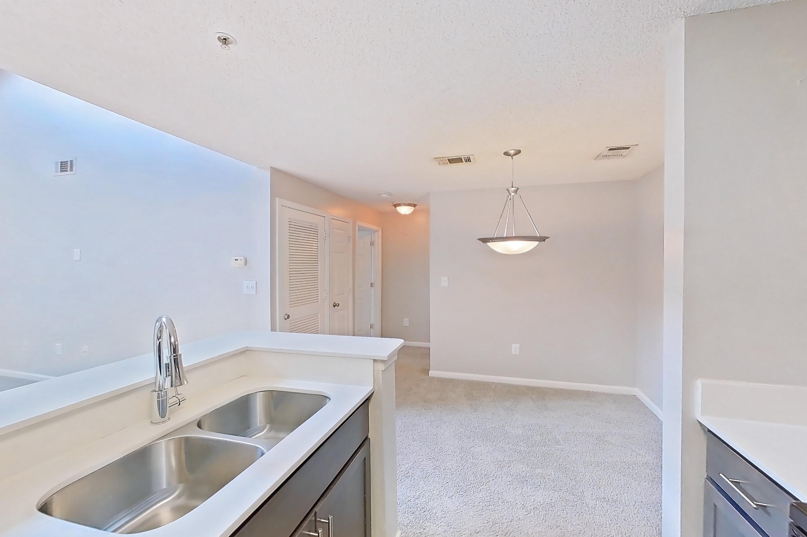 Kitchen with black appliances, dishwasher, electric range, light carpet, light countertops, light stone countertops, light wood-finish flooring, microwave, oven/range, and refrigerator, Apartment 533 at Walden Landing