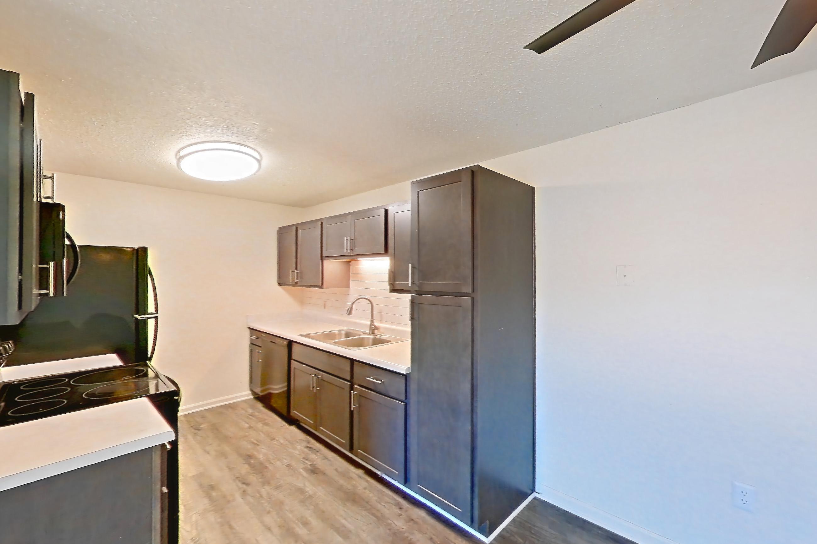 Dining room with dark wood-finish flooring, dishwasher, electric range, light countertops, oven/range, refrigerator, and stainless steel appliances, Apartment 64 at Woodwinds