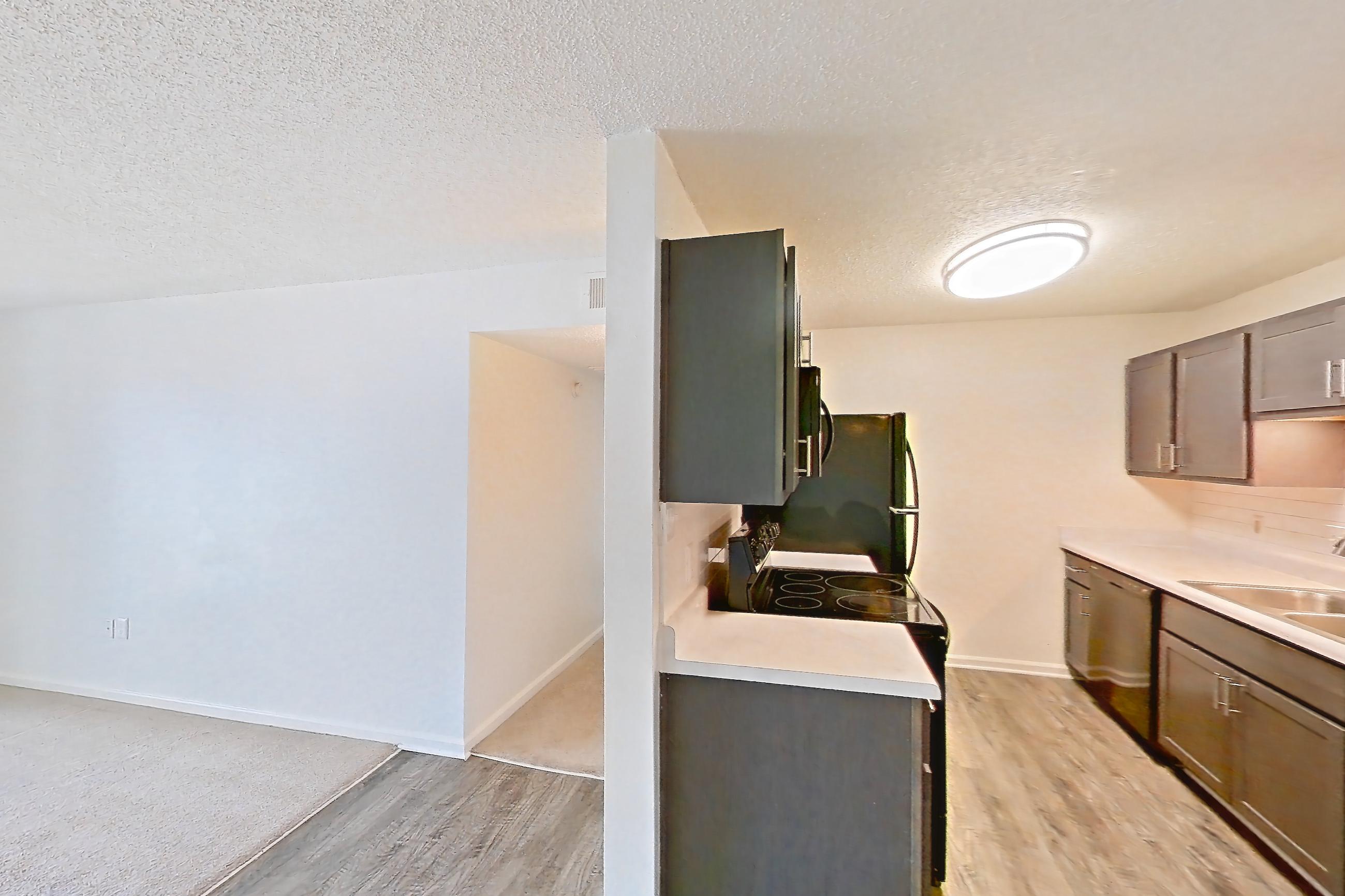 Dining room with dark wood-finish flooring, dishwasher, electric range, light countertops, oven/range, refrigerator, and stainless steel appliances, Apartment 64 at Woodwinds