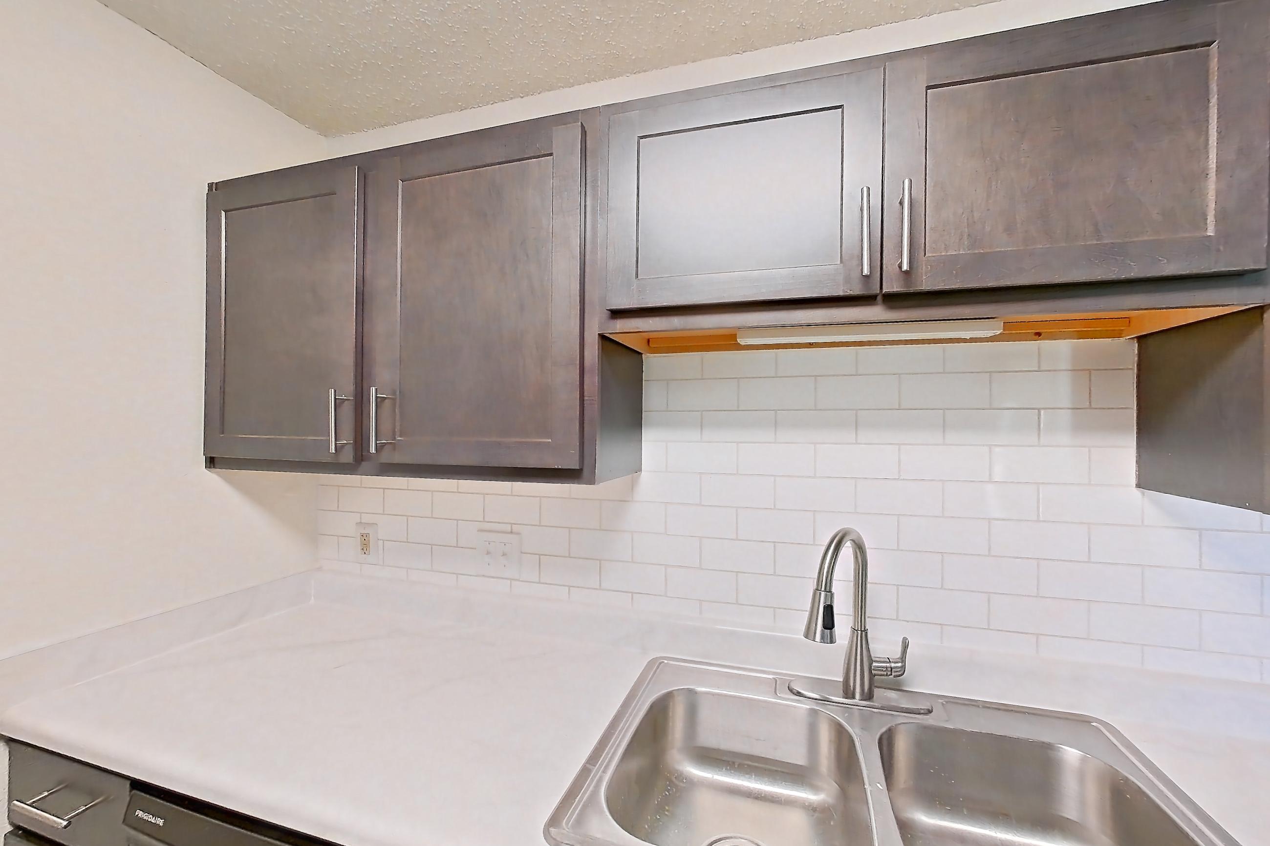 Kitchen with black appliances, dishwasher, electric range, light countertops, light wood-finish flooring, oven/range, range hood, and refrigerator, Apartment 48 at Woodwinds