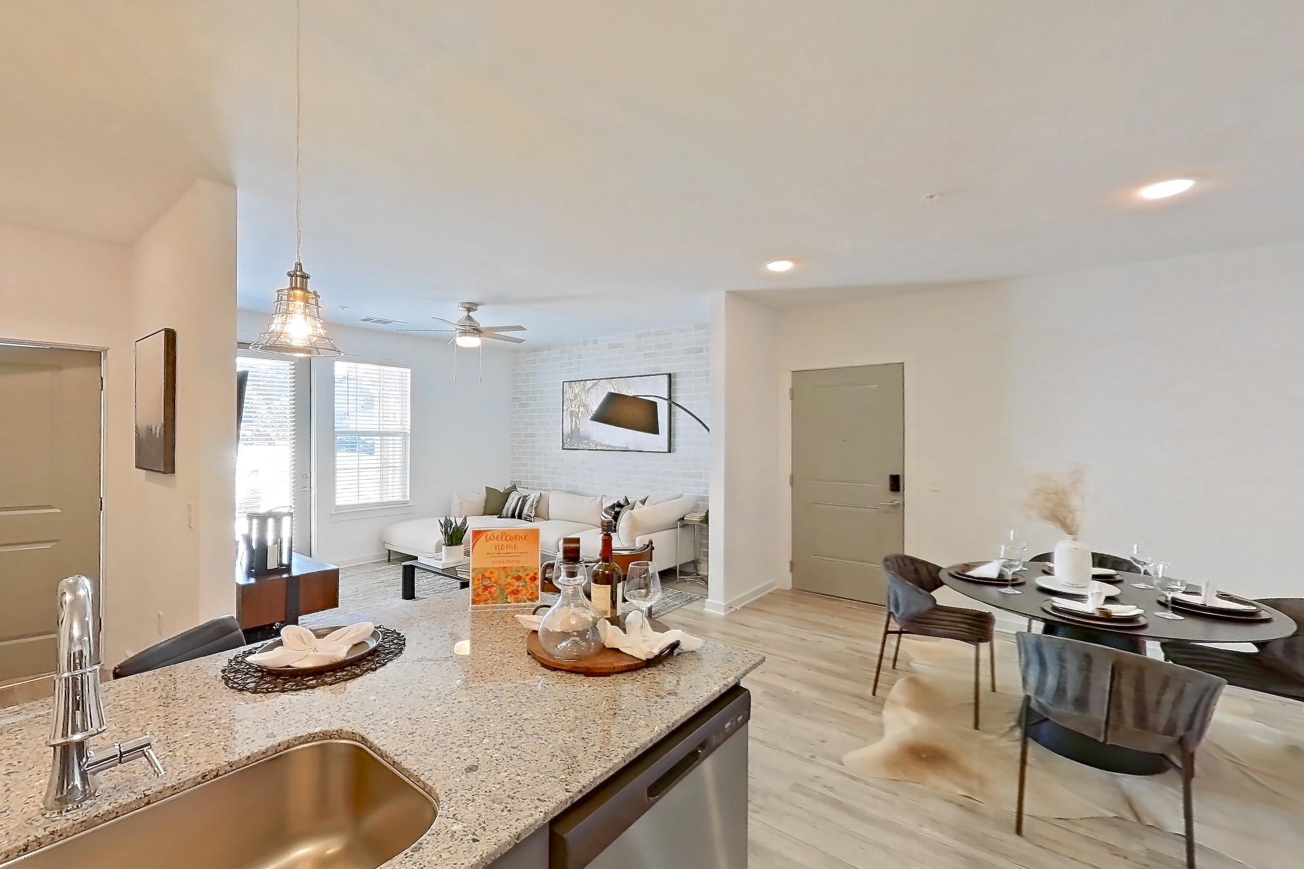 Kitchen with dishwasher, electric range, light stone countertops, light wood-finish flooring, oven/range, refrigerator, and stainless steel appliances, Apartment 1211-102 at Avril Cambridge Village