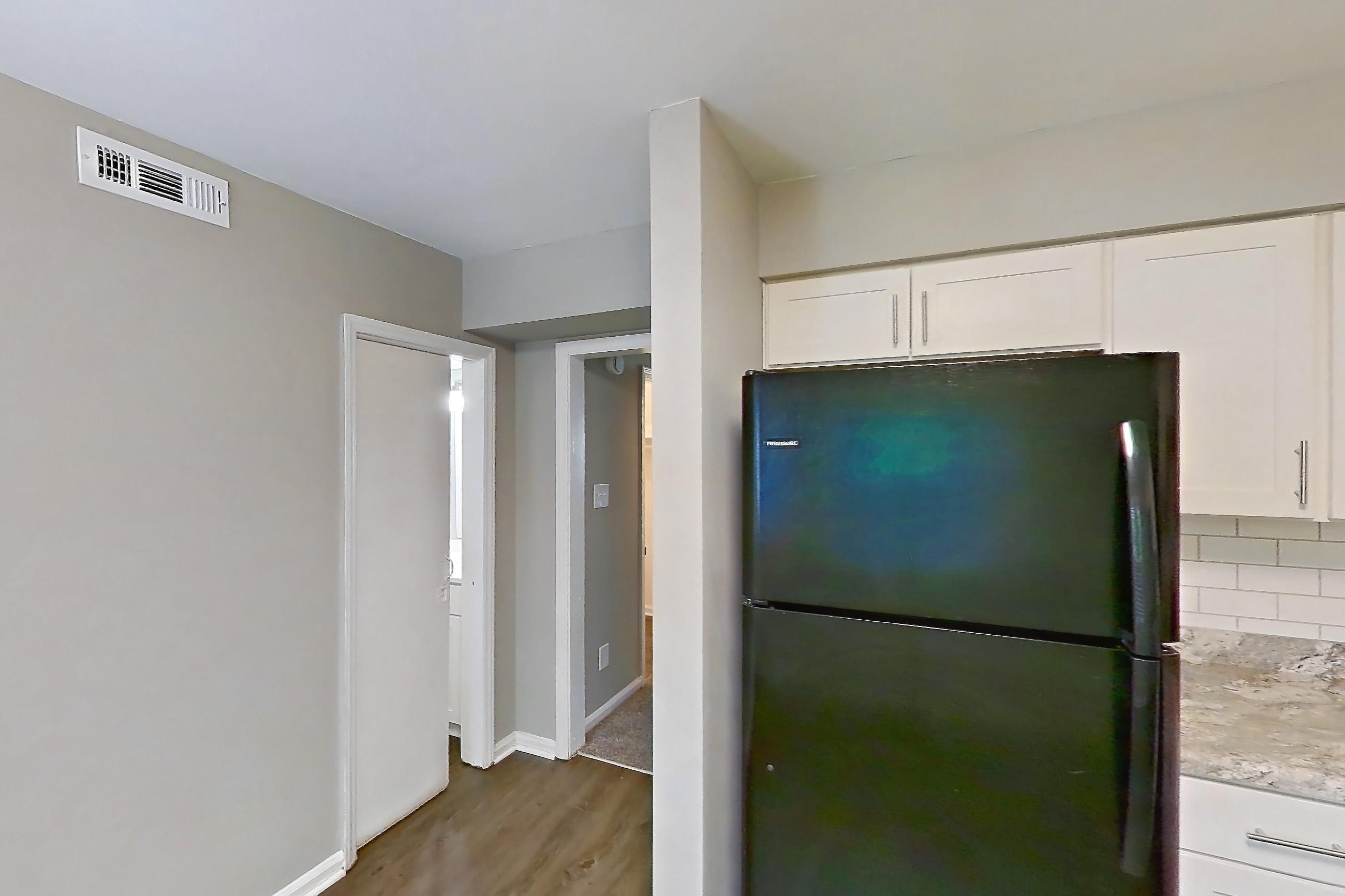 Kitchen with black appliances, dark wood-finish flooring, dishwasher, gas range, light countertops, microwave, oven/range, and refrigerator, Apartment 1260I at Carriage House & Azalea