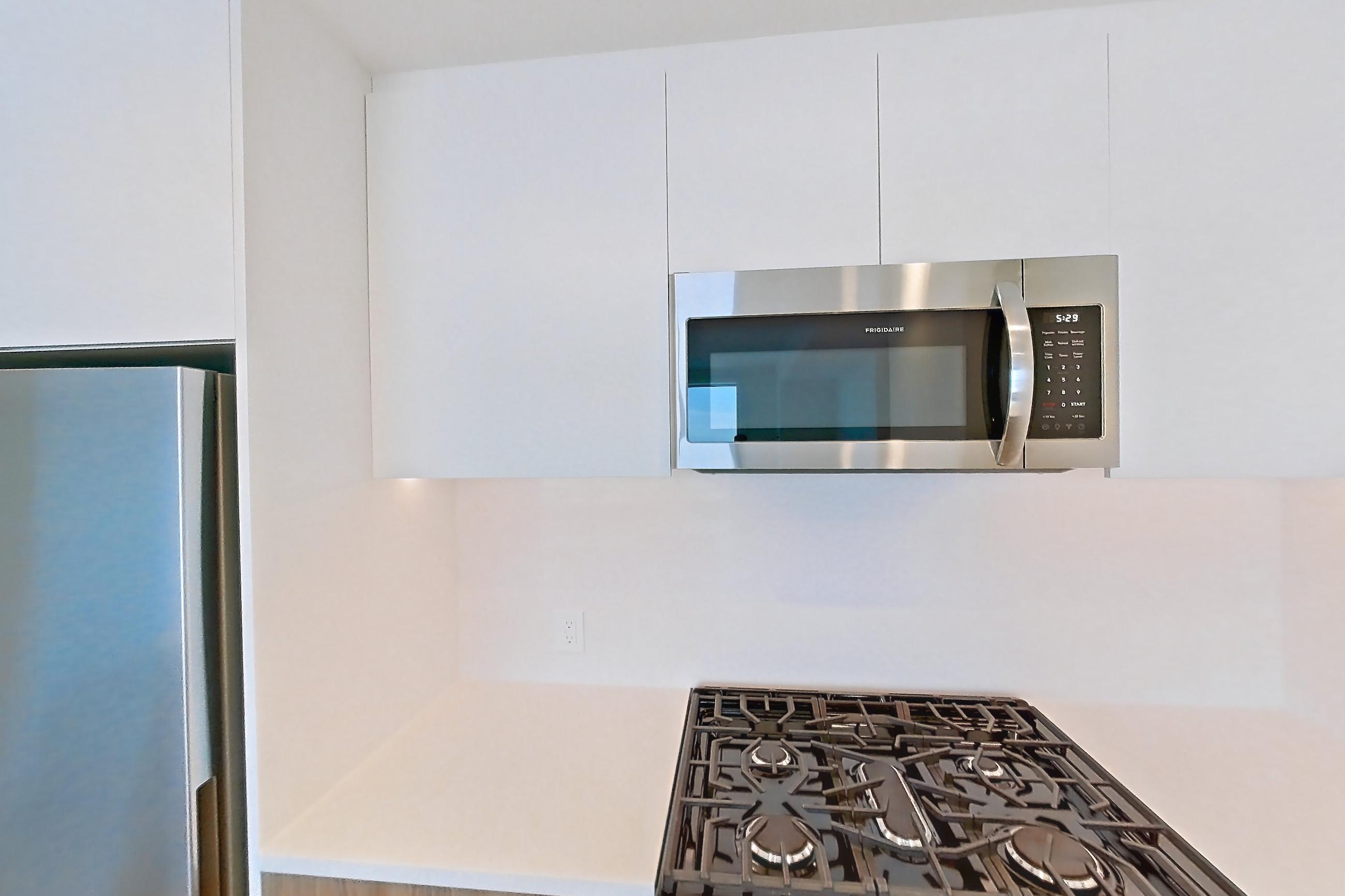 Kitchen with dishwasher, gas range, light countertops, light wood-finish flooring, oven/range, refrigerator, and stainless steel appliances, Apartment 62Q at Lumen