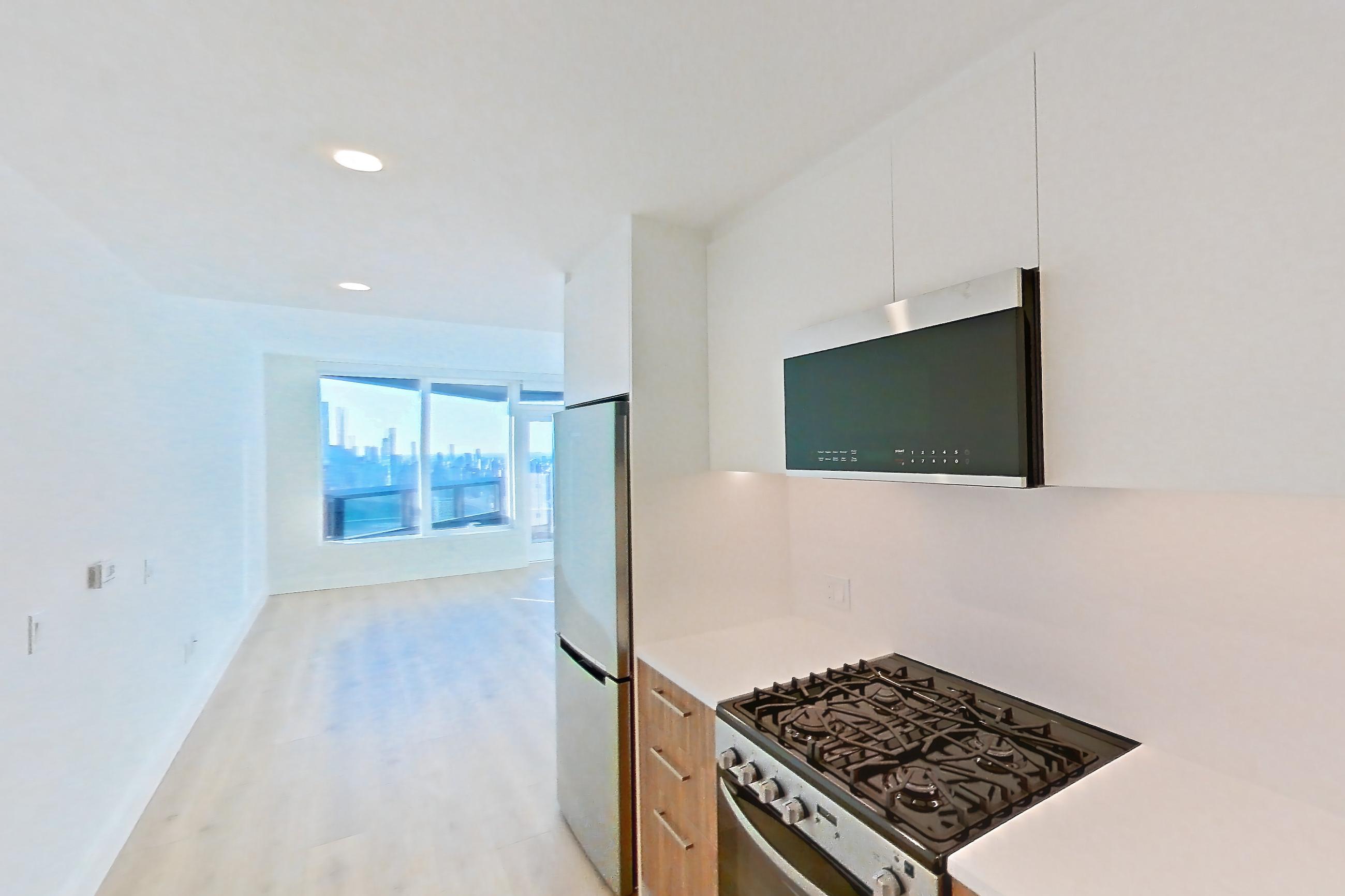 Kitchen with dishwasher, gas range, light countertops, light wood-finish flooring, oven/range, refrigerator, and stainless steel appliances, Apartment 56G at Lumen