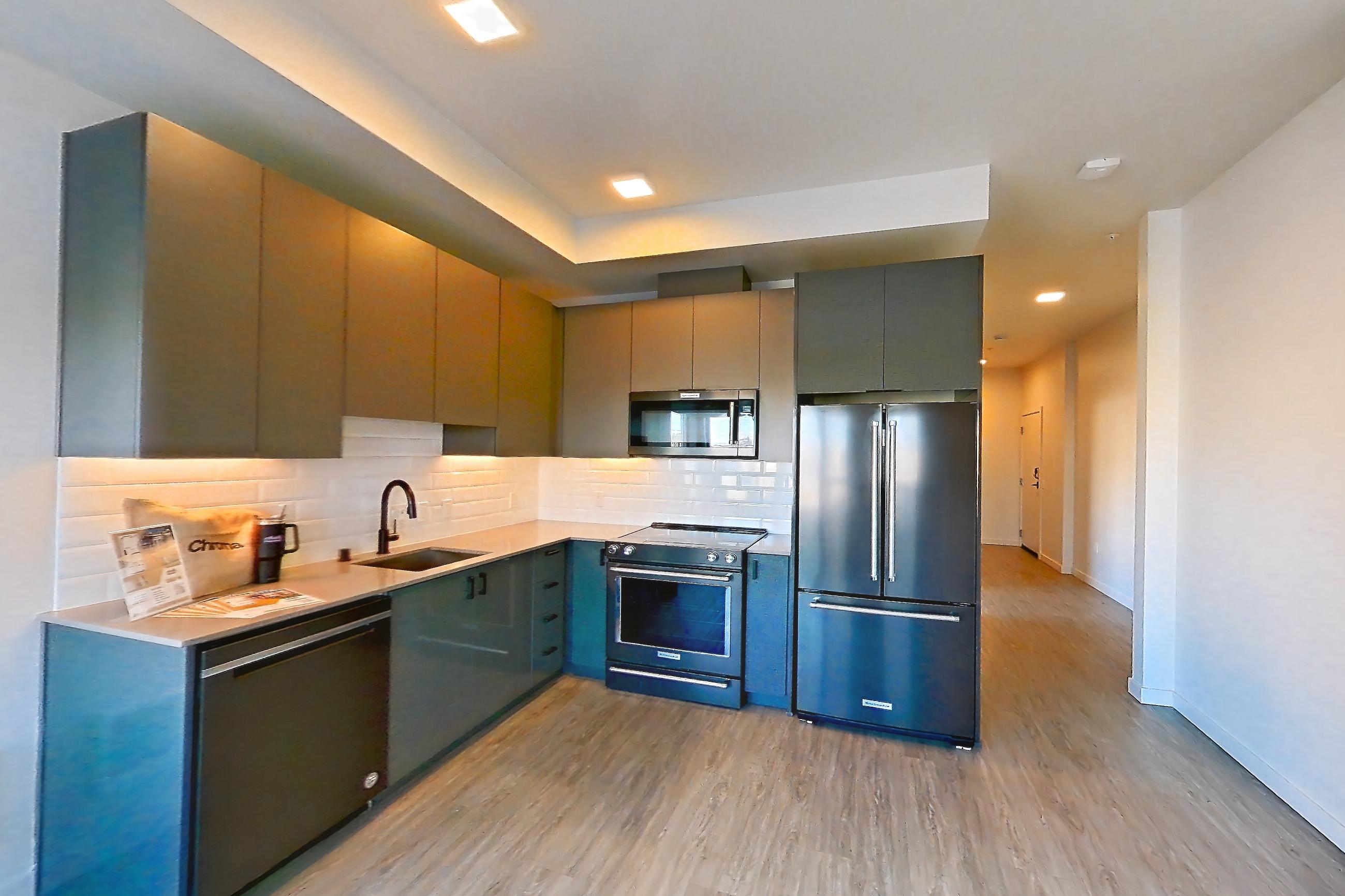 Living room with black appliances, dishwasher, electric range, light stone countertops, light wood-finish flooring, oven/range, refrigerator, and stainless steel appliances, Apartment 711W at Chroma