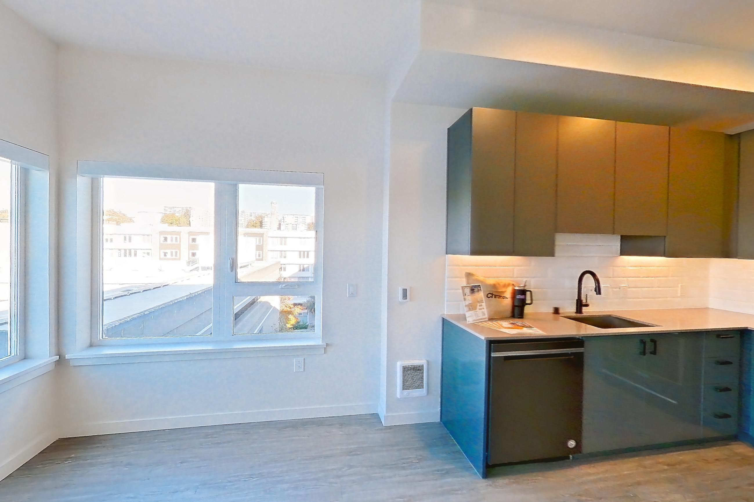 Living room with black appliances, dishwasher, electric range, light stone countertops, light wood-finish flooring, oven/range, refrigerator, and stainless steel appliances, Apartment 711W at Chroma