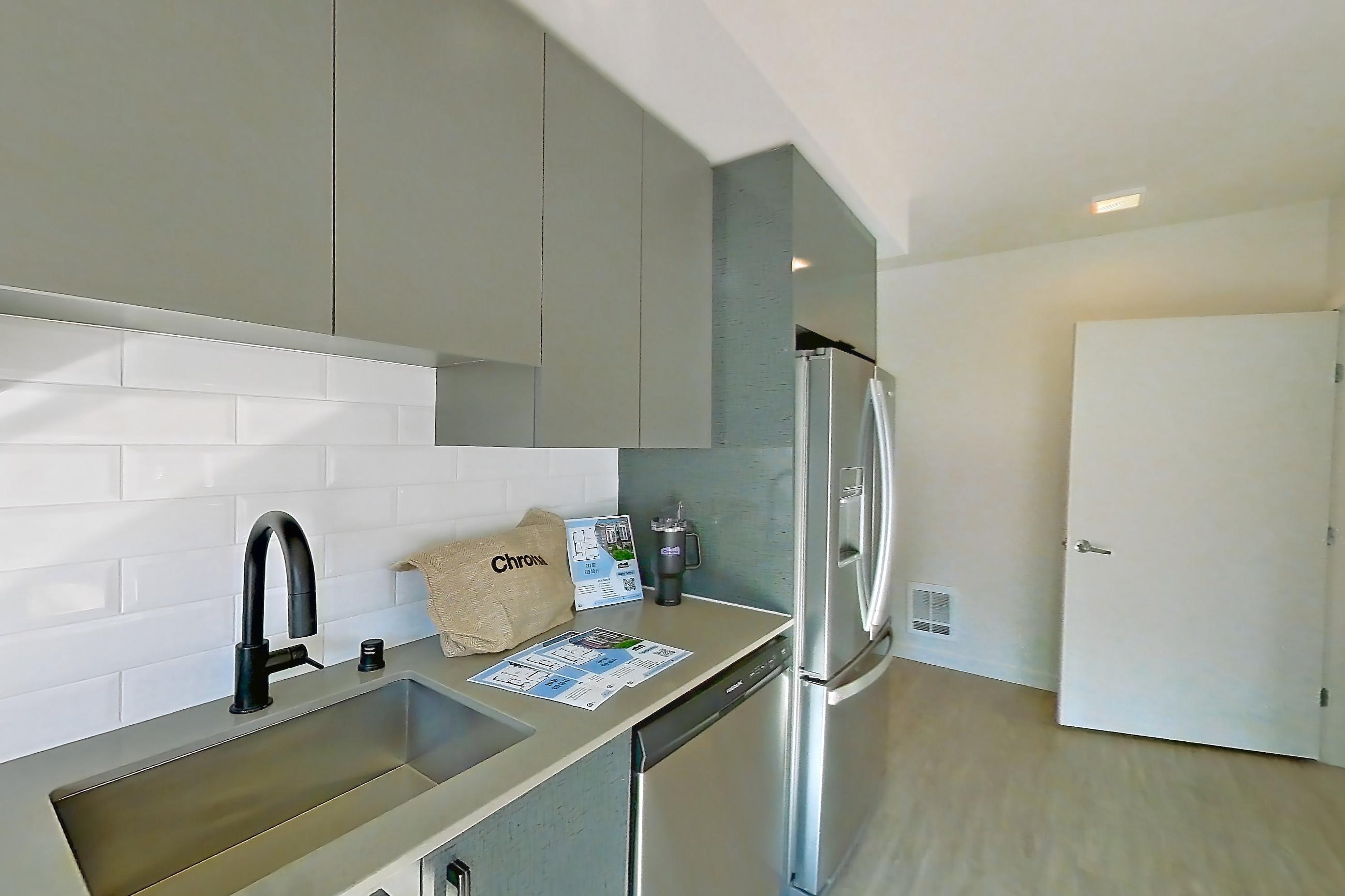 Kitchen with dishwasher, electric range, light countertops, light wood-finish flooring, oven/range, refrigerator, and stainless steel appliances, Unit 525W at Chroma