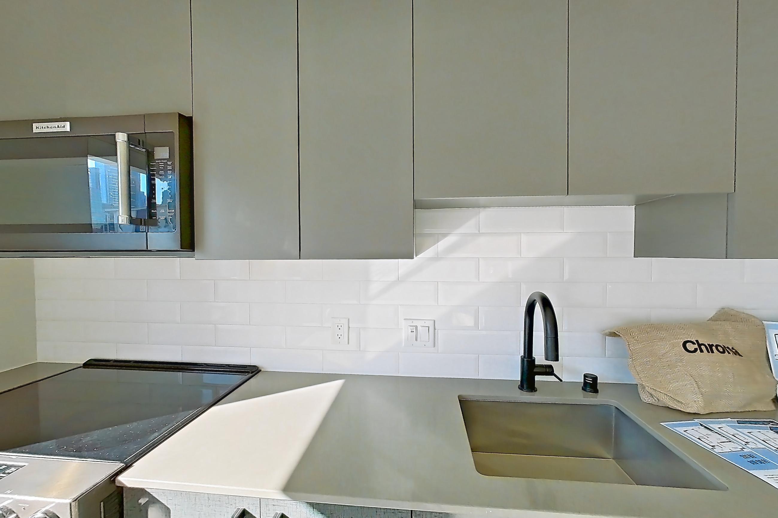 Kitchen with dishwasher, electric range, light countertops, light wood-finish flooring, oven/range, refrigerator, and stainless steel appliances, Unit 525W at Chroma