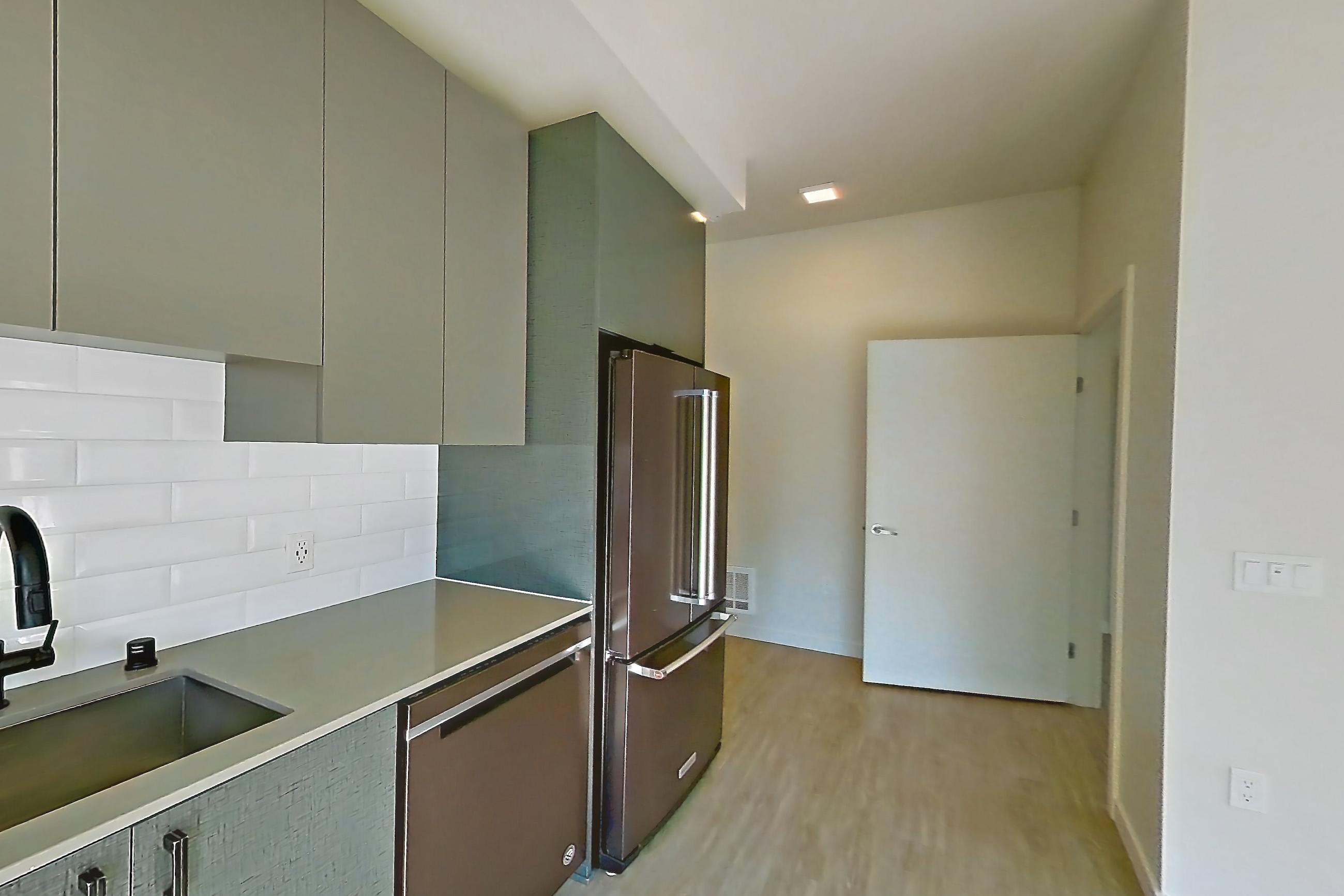 Kitchen with light countertops, light wood-finish flooring, oven/range, refrigerator, and stainless steel appliances, Unit 725W at Chroma