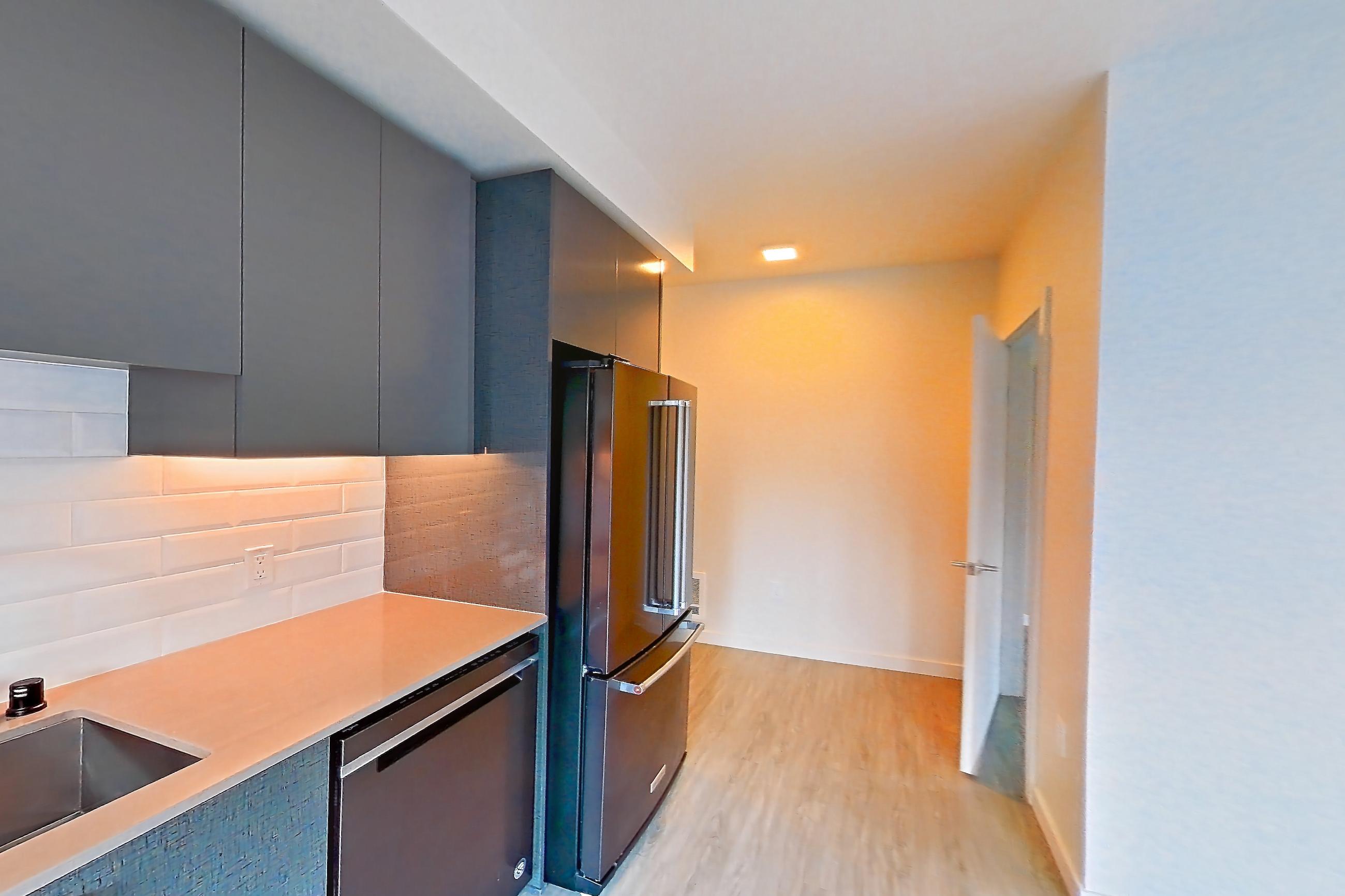 Kitchen with dishwasher, electric range, light countertops, light stone countertops, light wood-finish flooring, oven/range, refrigerator, and stainless steel appliances, Apartment 325W at Chroma