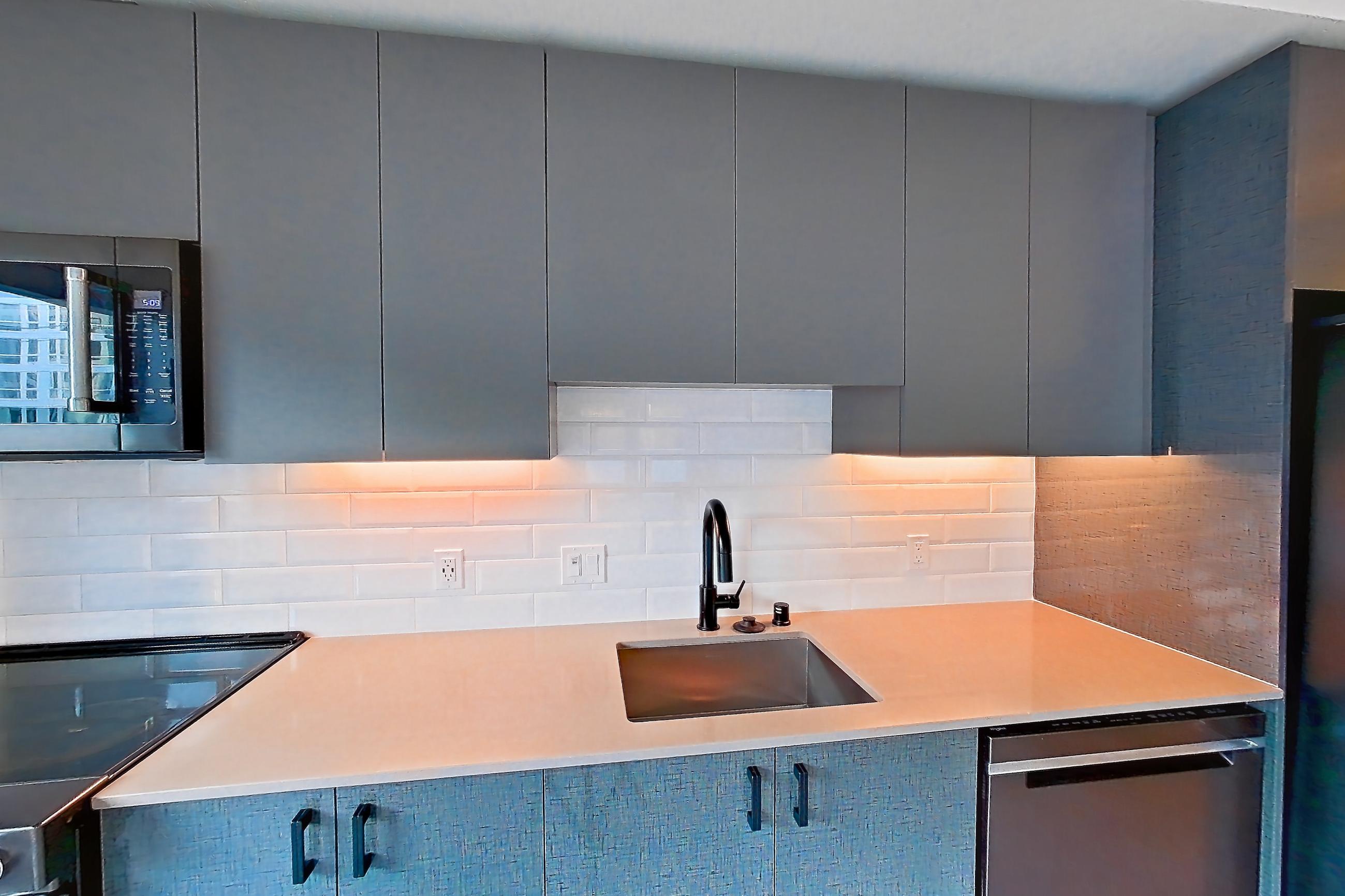 Kitchen with dishwasher, electric range, light countertops, light stone countertops, light wood-finish flooring, oven/range, refrigerator, and stainless steel appliances, Apartment 325W at Chroma