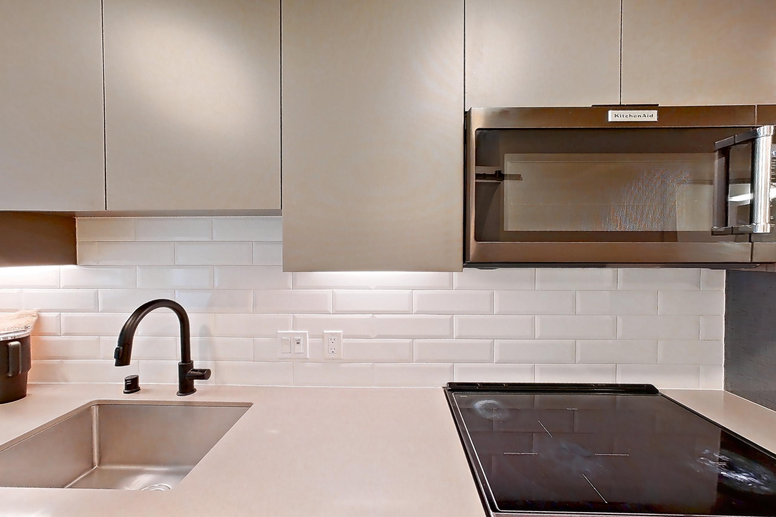 Kitchen with electric range, light countertops, light stone countertops, light wood-finish flooring, oven/range, refrigerator, and stainless steel appliances, Apartment 107 at Chroma