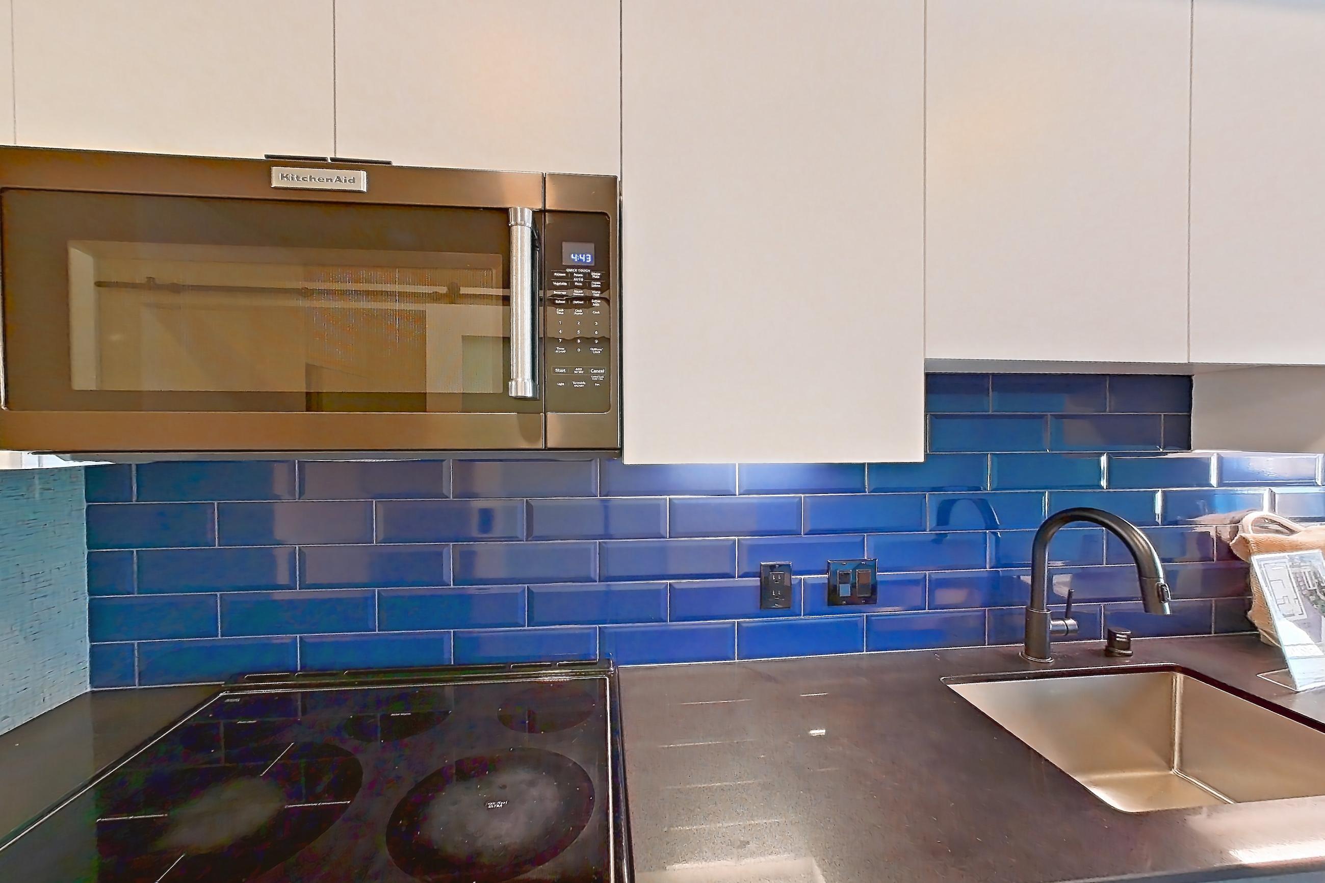 Kitchen with dark countertops, electric range, light countertops, light wood-finish flooring, microwave, oven/range, refrigerator, and stainless steel appliances, Apartment 408 at Chroma