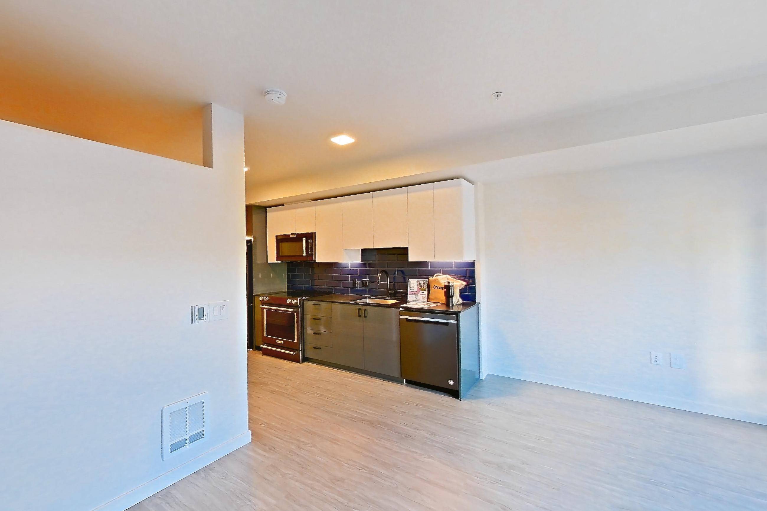 Living room with dishwasher, light wood-finish flooring, and stainless steel appliances, Apartment 408 at Chroma