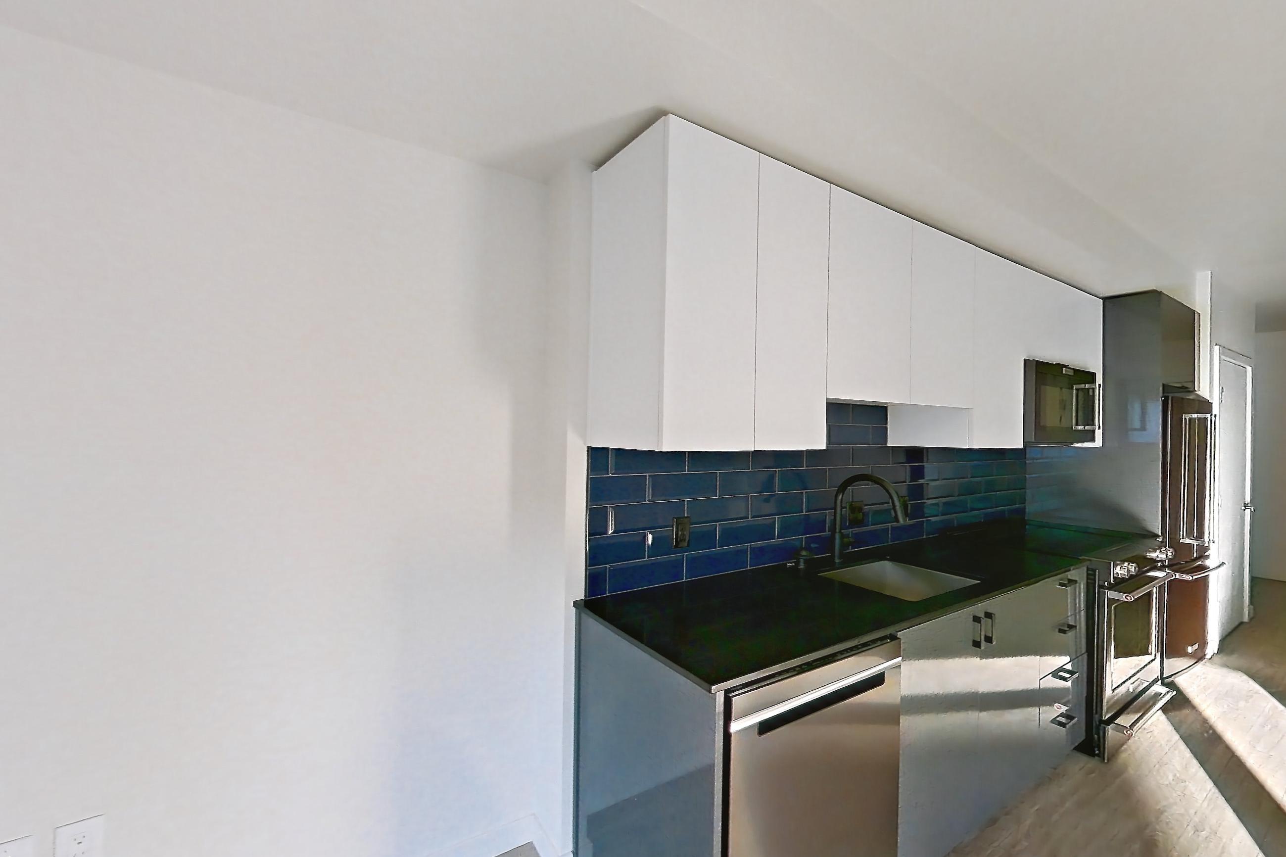 Living space with dark countertops and light wood-finish flooring, Apartment 604W at Chroma