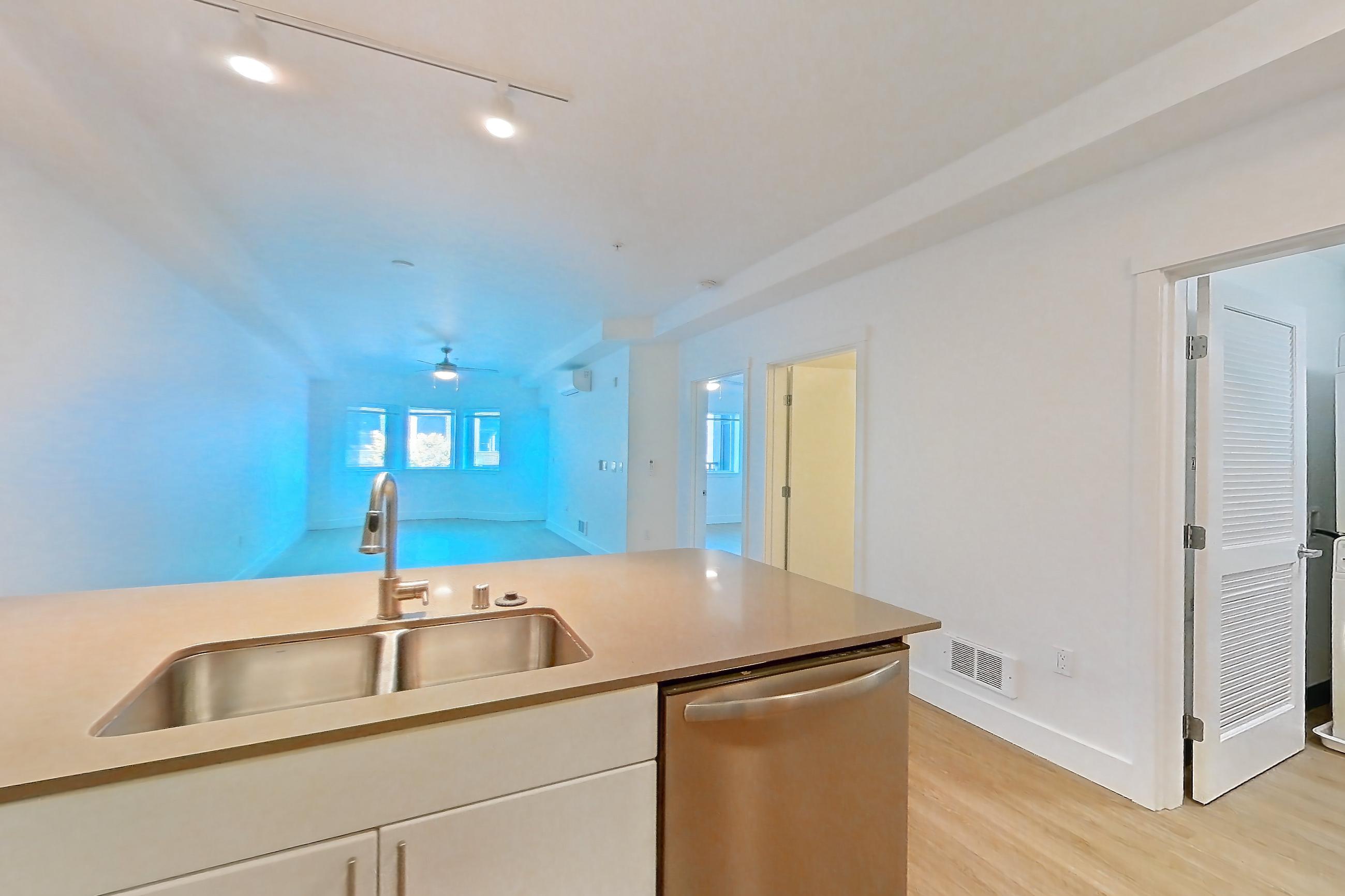 Kitchen with dishwasher, electric range, light countertops, light stone countertops, light wood-finish flooring, microwave, mini-split AC, oven/range, refrigerator, and stainless steel appliances, Unit 228 at The Waymark