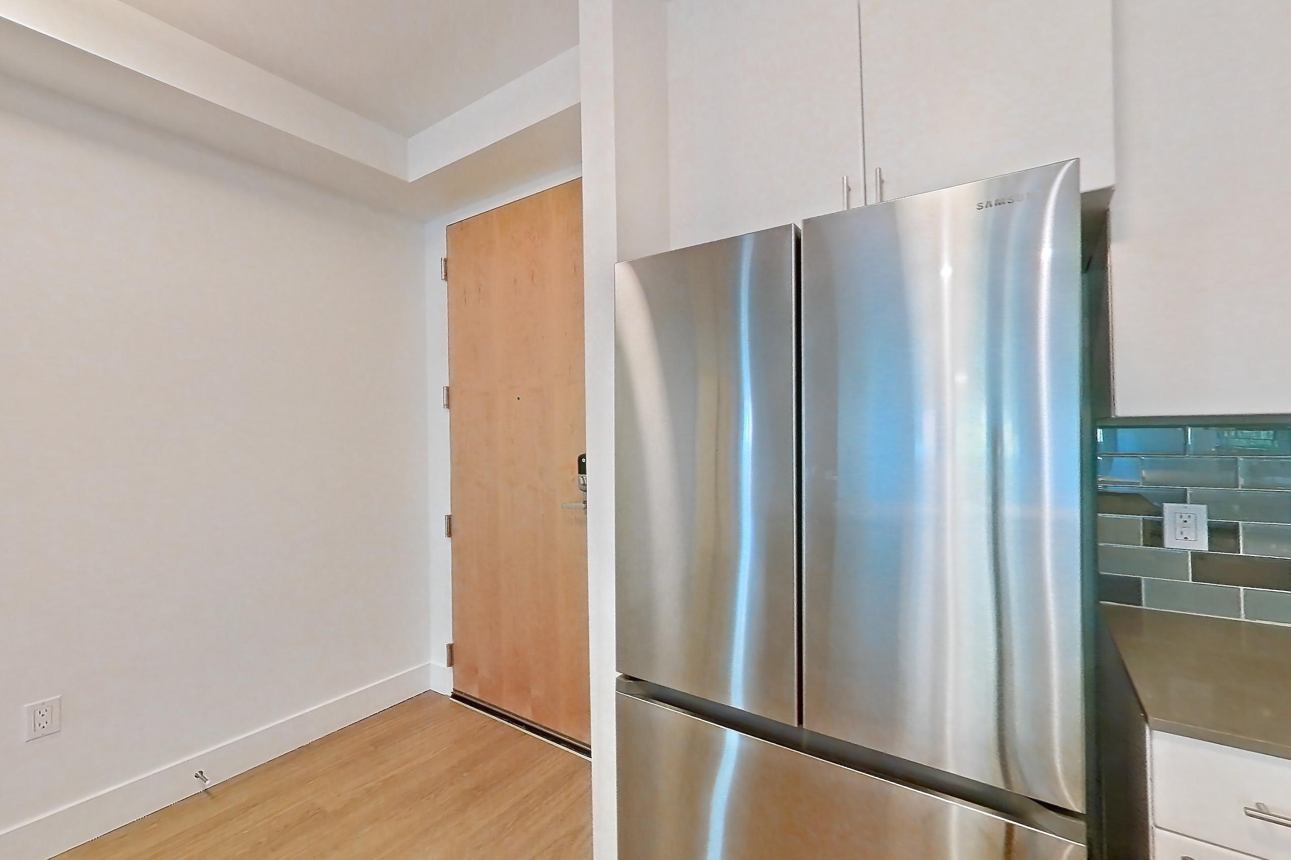 Kitchen with dishwasher, electric range, light countertops, light stone countertops, light wood-finish flooring, microwave, mini-split AC, oven/range, refrigerator, and stainless steel appliances, Unit 228 at The Waymark