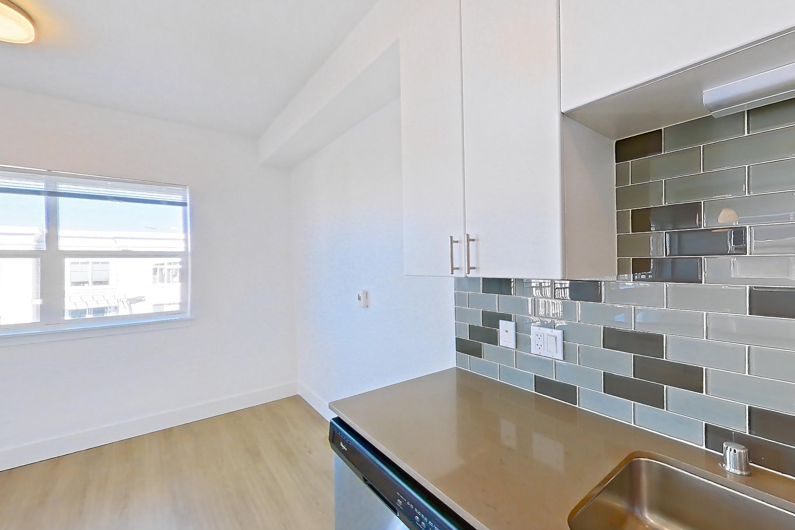 Kitchen with dishwasher, electric range, light countertops, light stone countertops, light wood-finish flooring, microwave, oven/range, refrigerator, and stainless steel appliances, Unit 720 at The Waymark