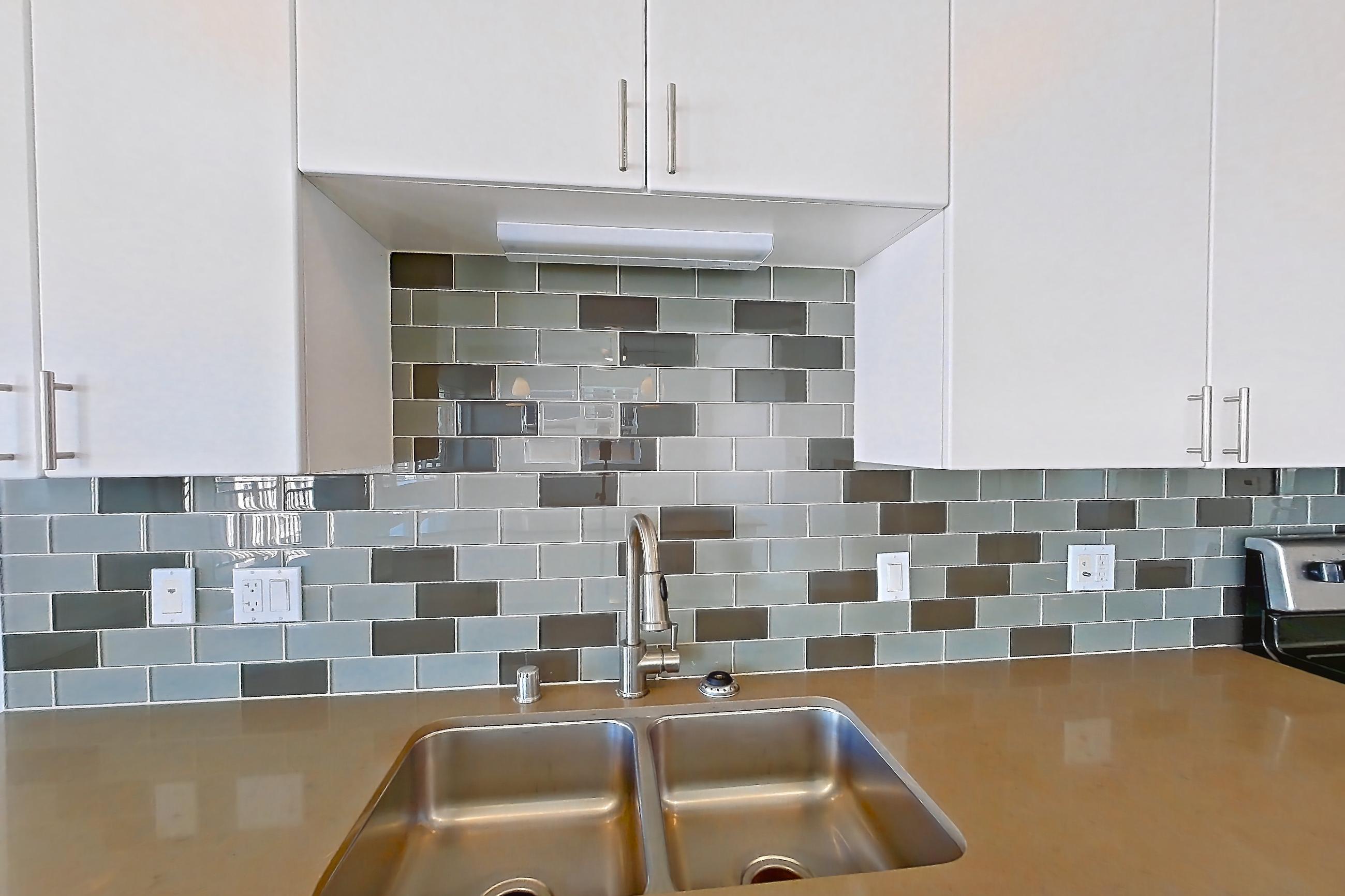Kitchen with dishwasher, electric range, light countertops, light stone countertops, light wood-finish flooring, microwave, oven/range, refrigerator, and stainless steel appliances, Unit 720 at The Waymark