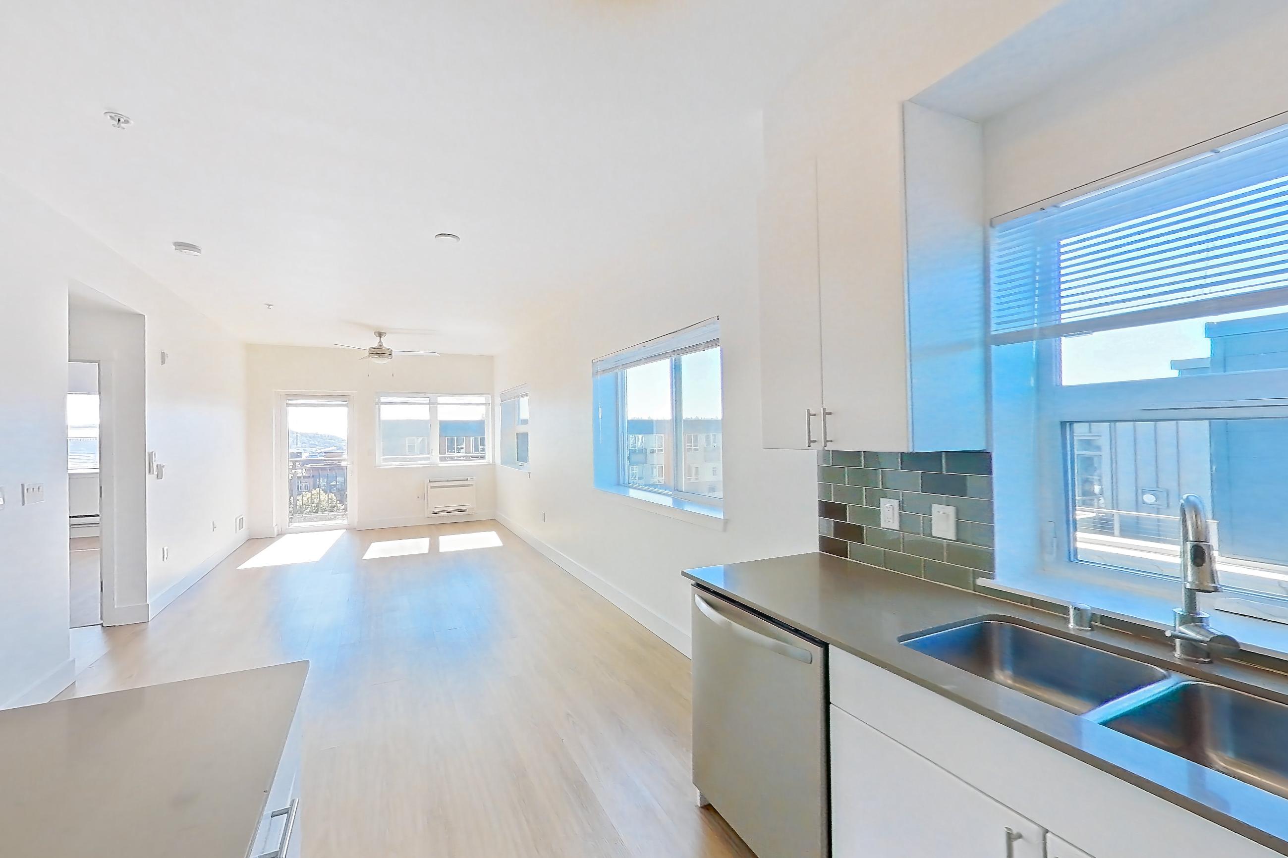 Kitchen with dishwasher, electric range, light countertops, light wood-finish flooring, microwave, oven/range, refrigerator, and stainless steel appliances, Unit 811 at The Waymark
