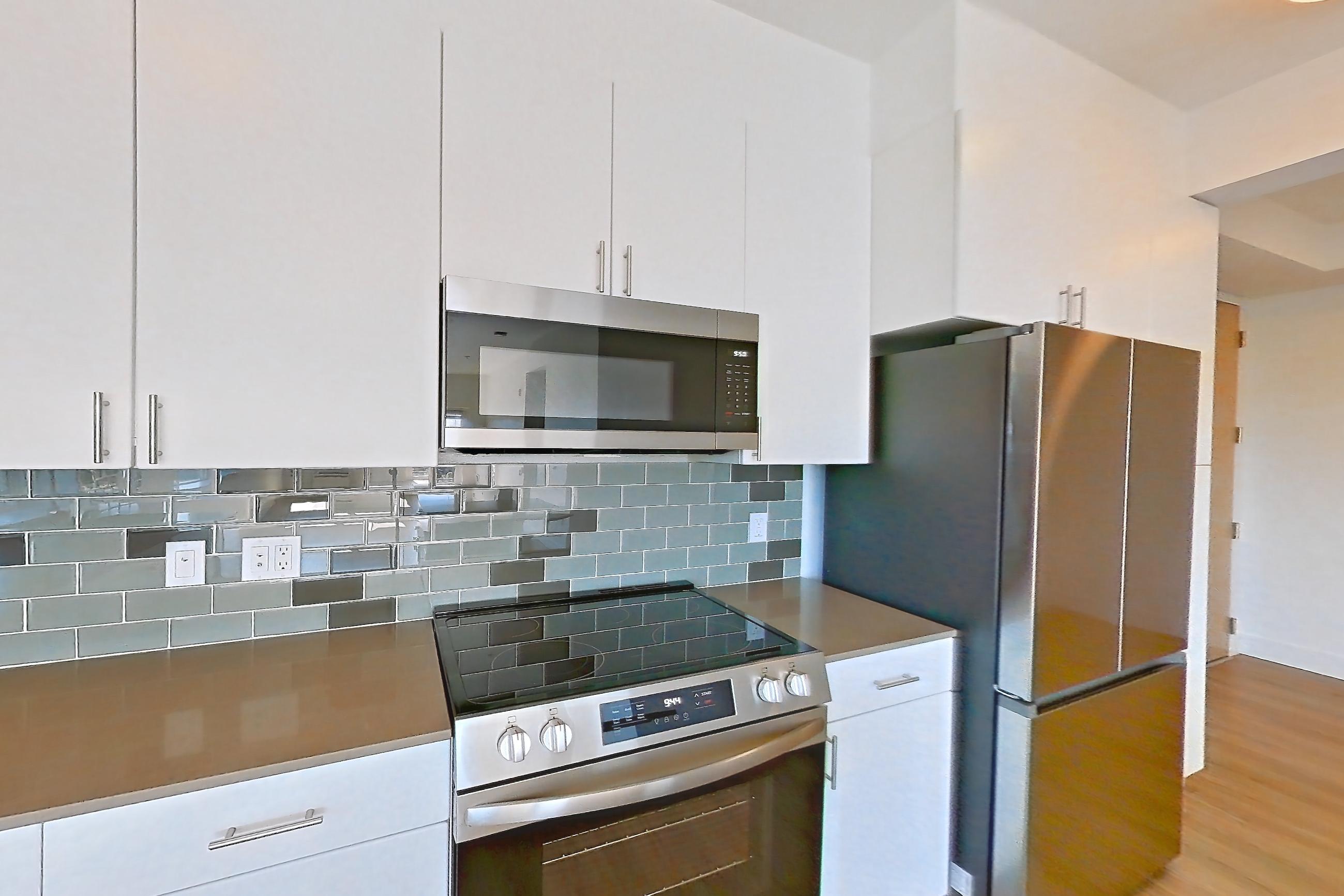 Kitchen with dishwasher, electric range, light countertops, light wood-finish flooring, microwave, oven/range, refrigerator, and stainless steel appliances, Unit 811 at The Waymark