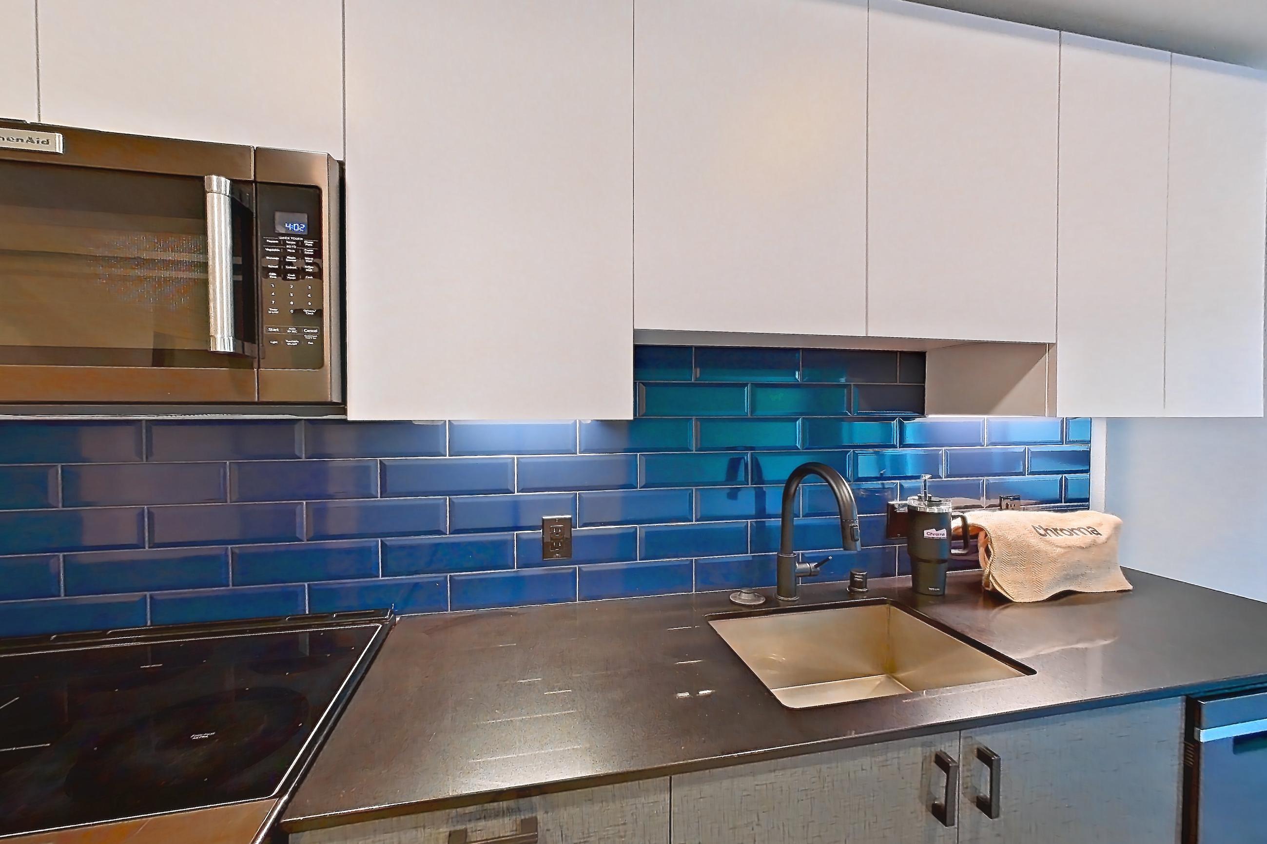 Kitchen with dark countertops, light countertops, light wood-finish flooring, microwave, oven/range, refrigerator, and stainless steel appliances, Unit 409W at Chroma