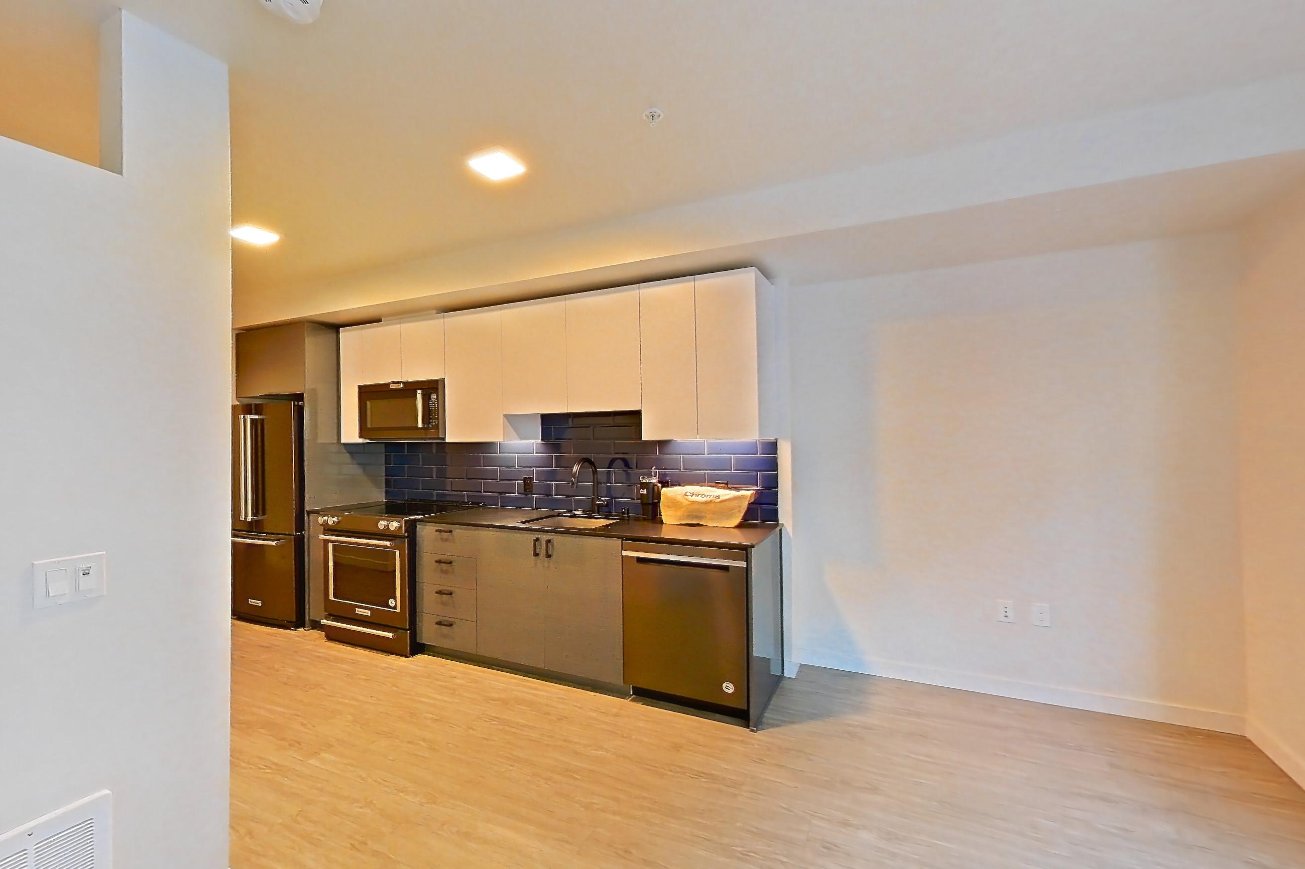 Living room with dishwasher, light wood-finish flooring, and stainless steel appliances, Unit 409W at Chroma