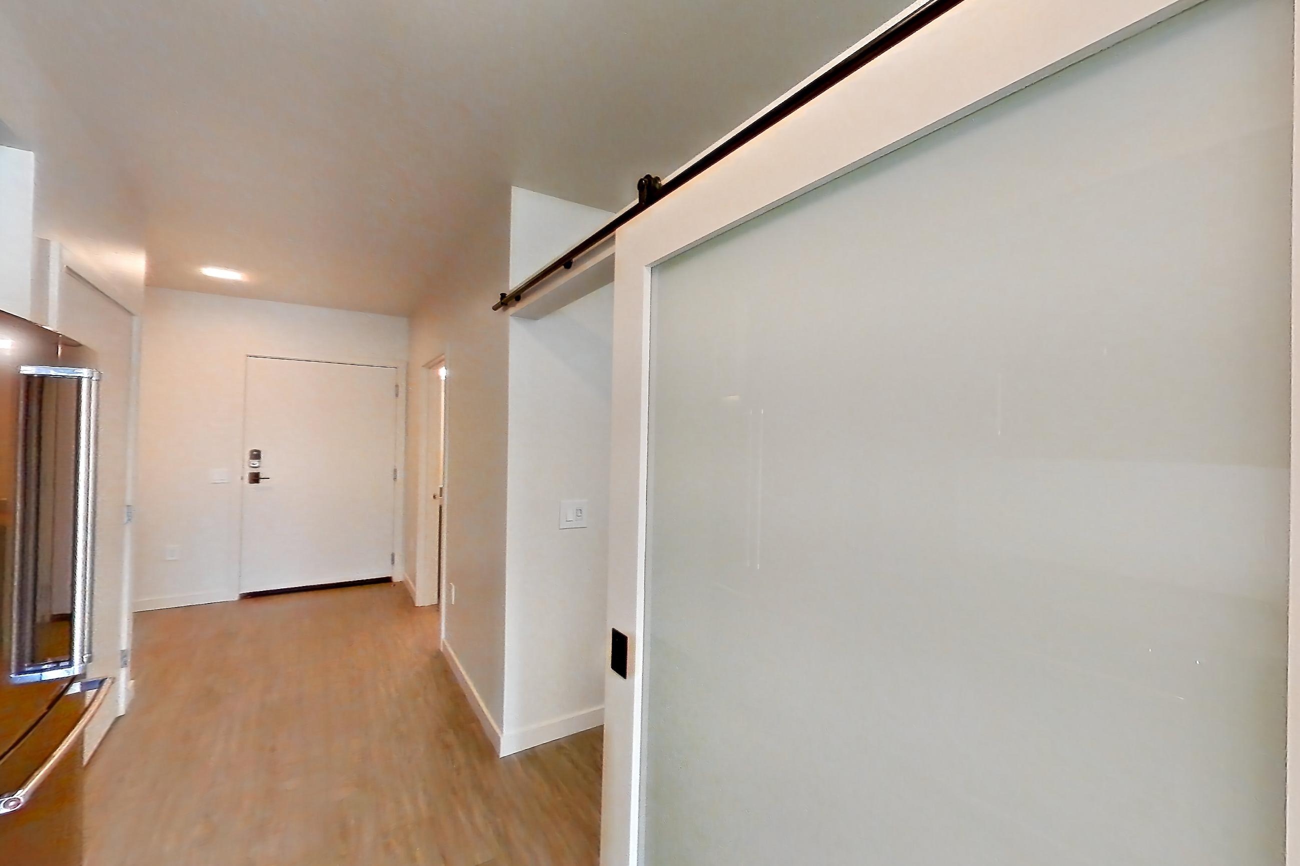 Kitchen with dishwasher, electric range, light countertops, light stone countertops, light wood-finish flooring, oven/range, refrigerator, stainless steel appliances, and water & ice dispenser, Apartment 515 at Chroma