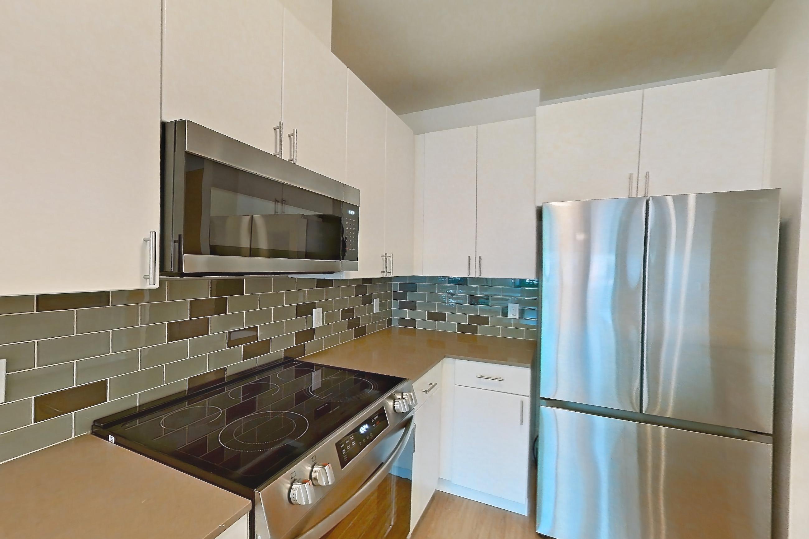 Kitchen with dishwasher, electric range, light countertops, light wood-finish flooring, oven/range, refrigerator, and stainless steel appliances, Apartment 534 at The Waymark