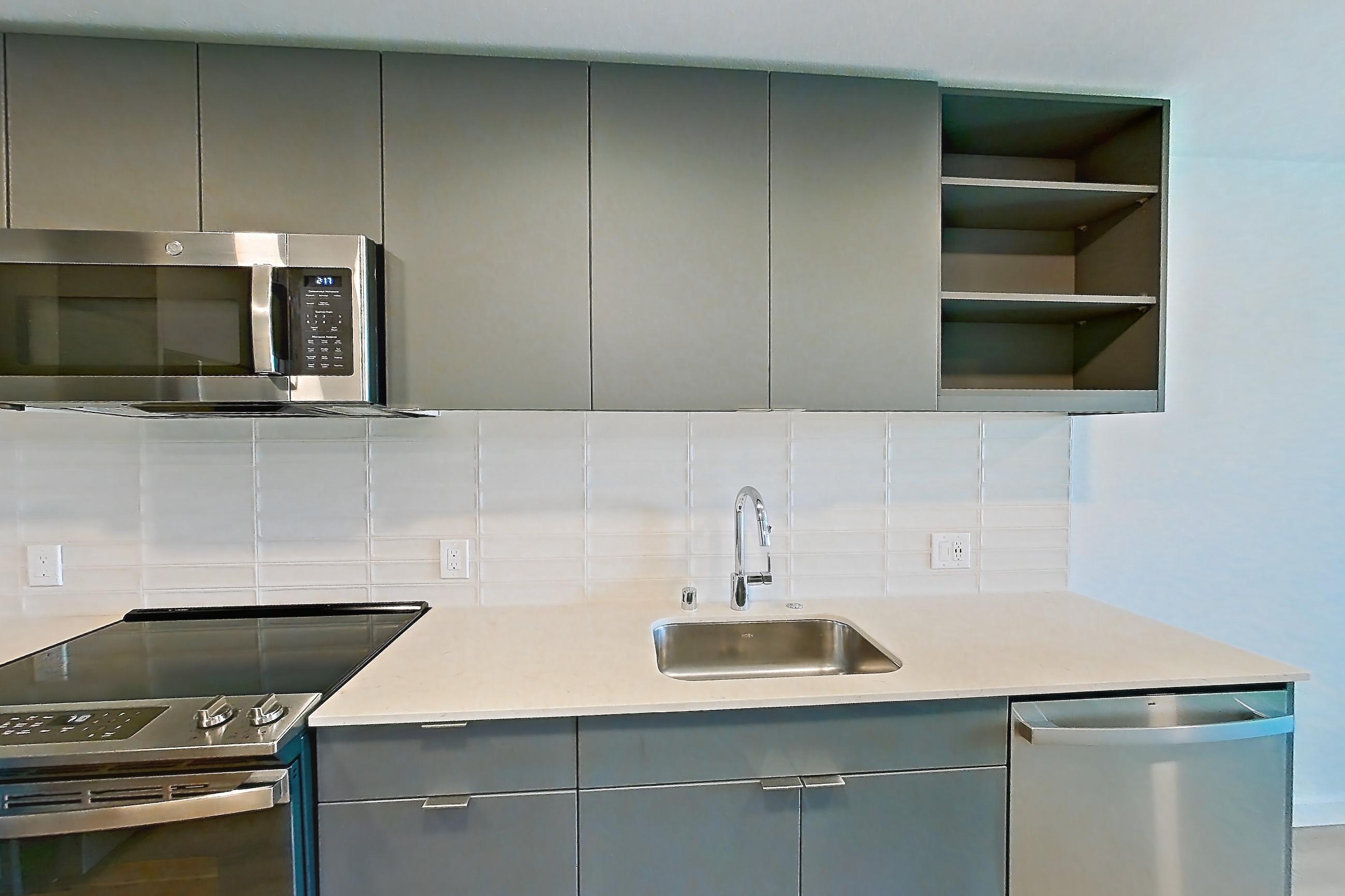 Kitchen with dishwasher, electric range, light countertops, light stone countertops, light wood-finish flooring, microwave, oven/range, refrigerator, and stainless steel appliances, Unit 174 at Arlo