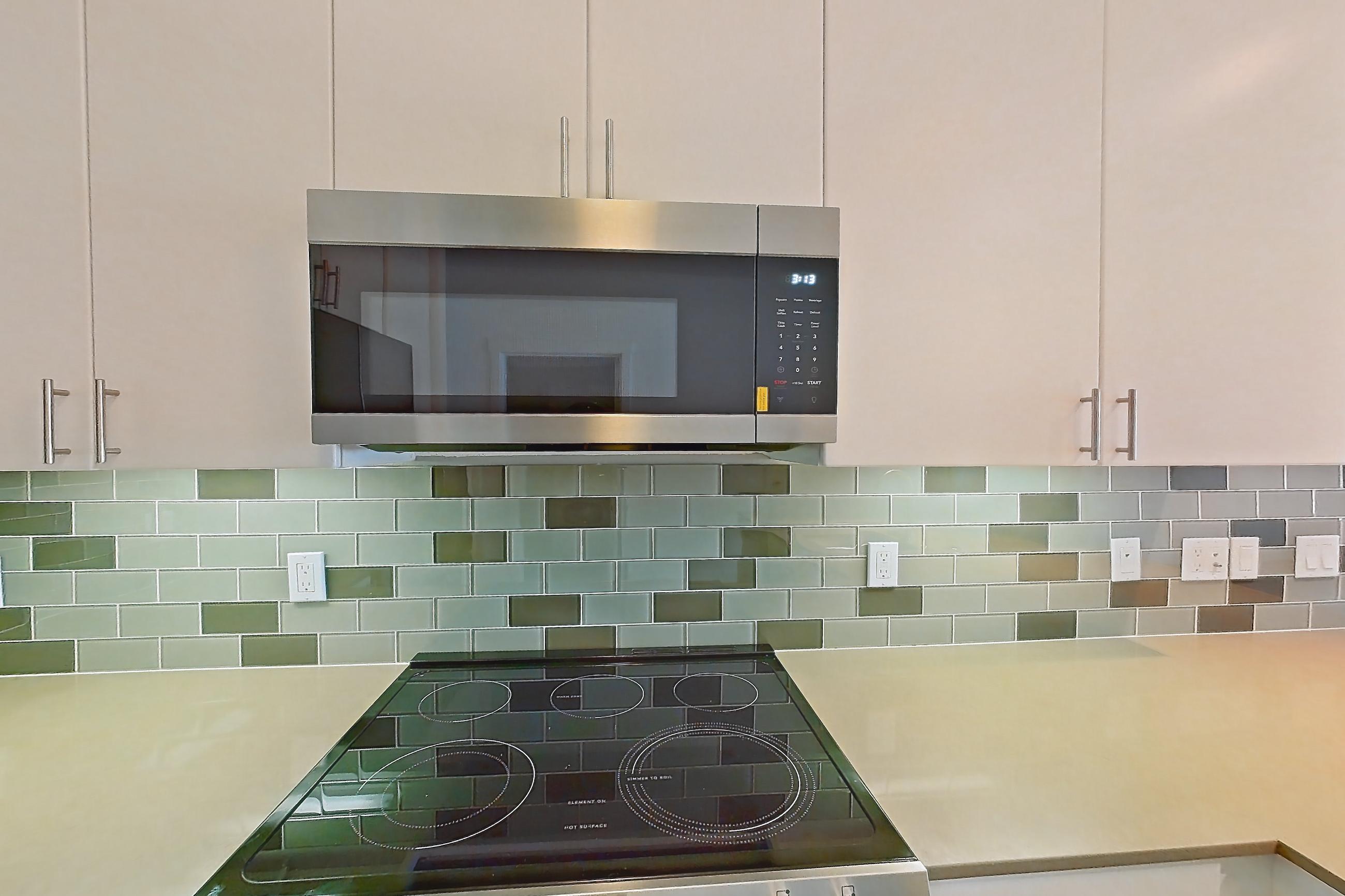 Kitchen with dishwasher, electric range, light countertops, light wood-finish flooring, microwave, oven/range, refrigerator, and stainless steel appliances, Apartment 329 at The Waymark