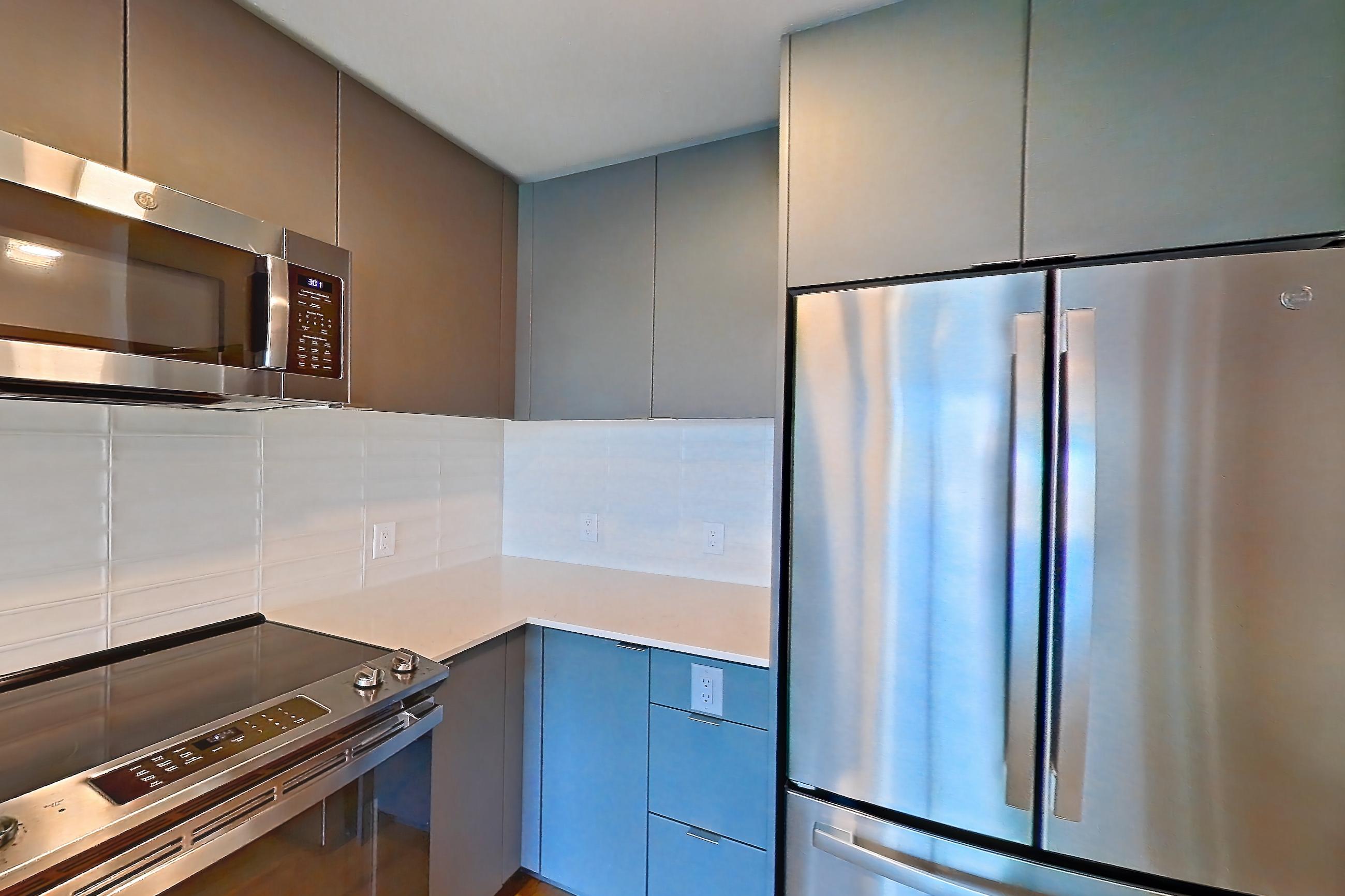 Kitchen with dishwasher, electric range, light countertops, light stone countertops, light wood-finish flooring, microwave, oven/range, refrigerator, and stainless steel appliances, Unit 376 at Arlo