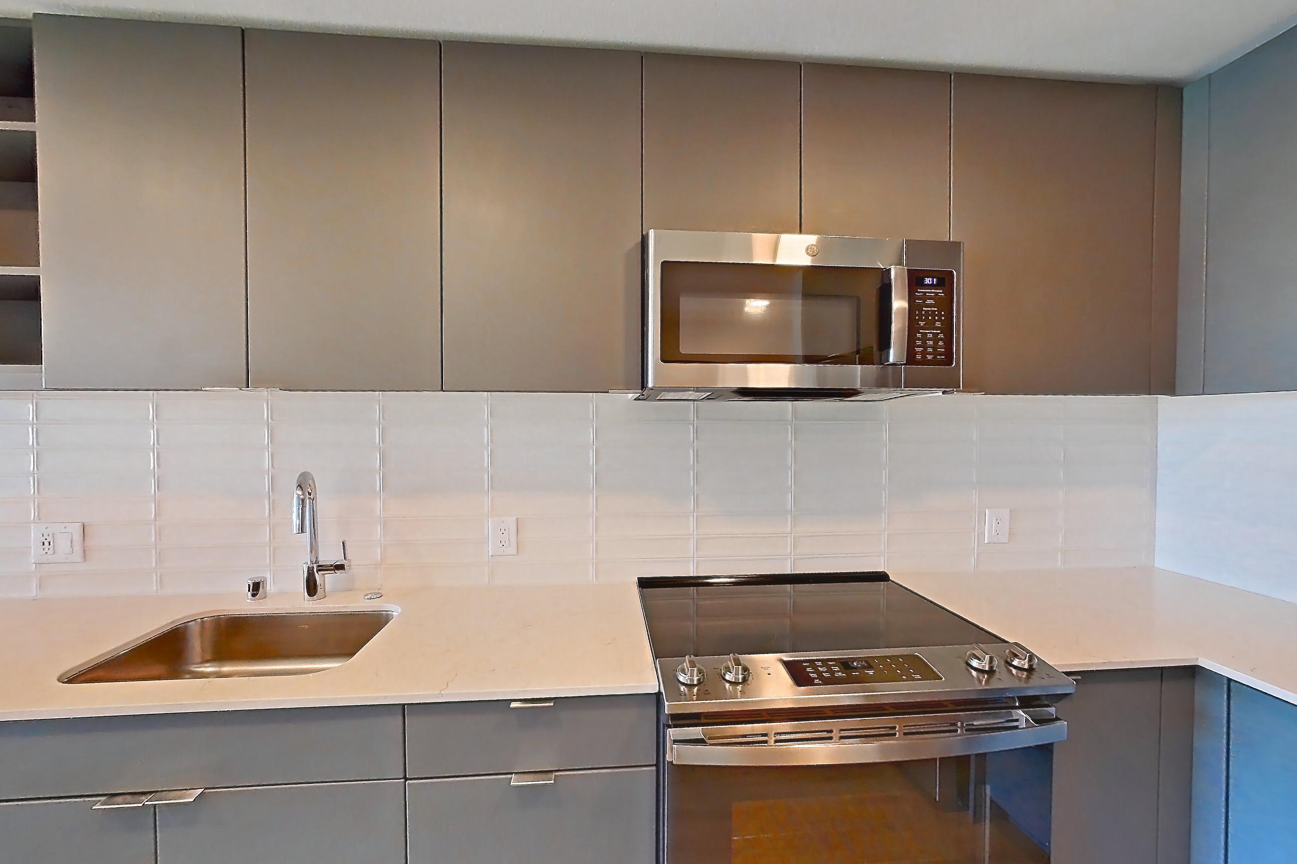 Kitchen with dishwasher, electric range, light countertops, light stone countertops, light wood-finish flooring, microwave, oven/range, refrigerator, and stainless steel appliances, Unit 376 at Arlo