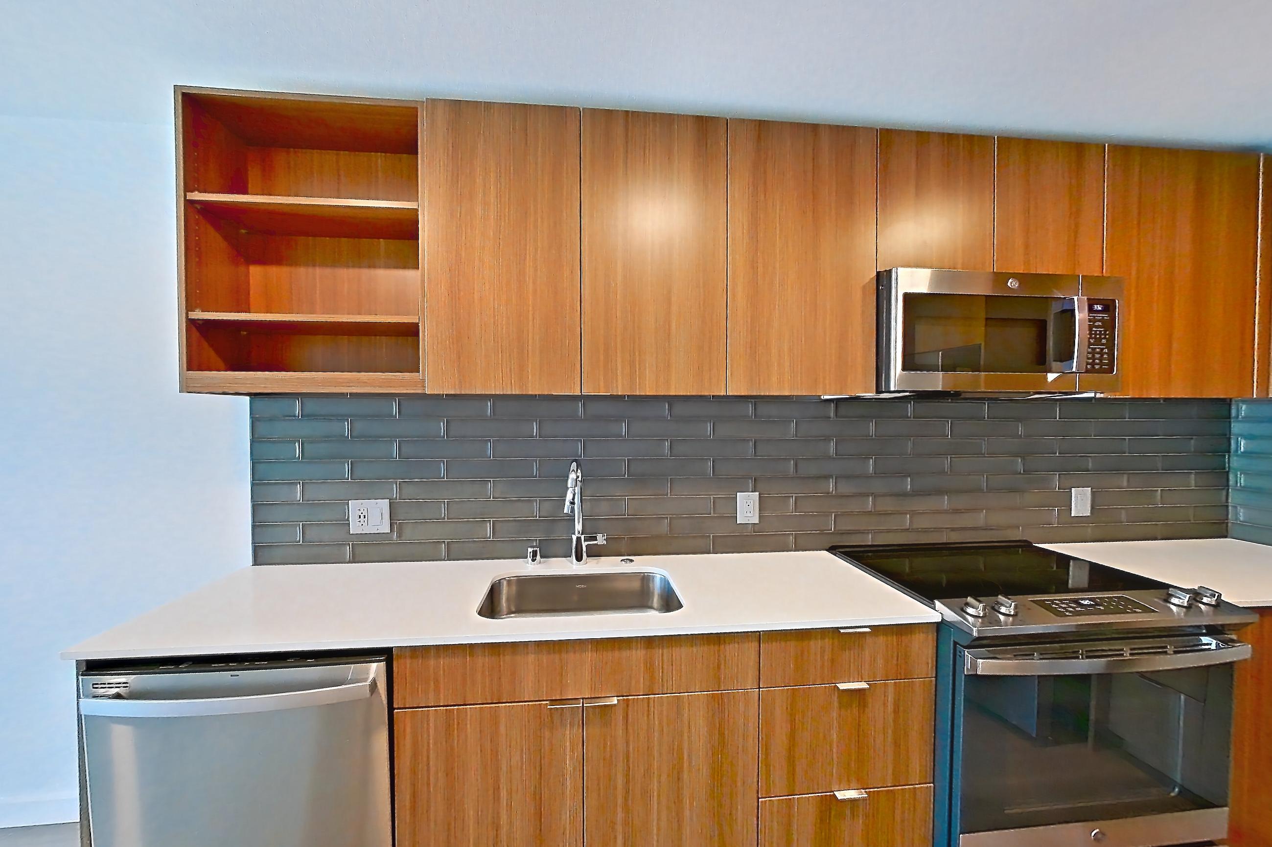 Kitchen with dishwasher, electric range, light countertops, light stone countertops, light wood-finish flooring, oven/range, refrigerator, and stainless steel appliances, Unit 438 at Arlo
