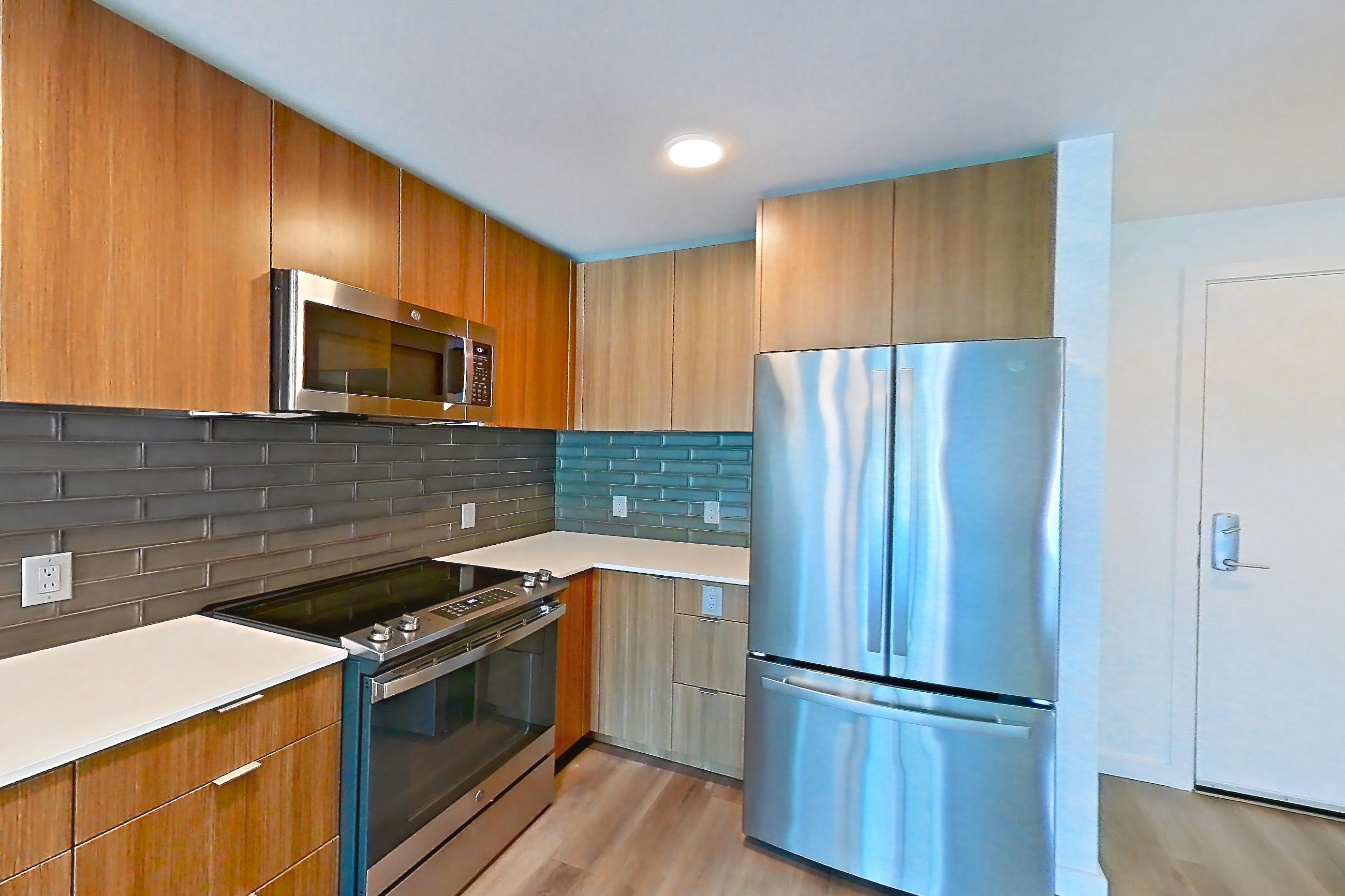 Kitchen with dishwasher, electric range, light countertops, light stone countertops, light wood-finish flooring, oven/range, refrigerator, and stainless steel appliances, Unit 438 at Arlo