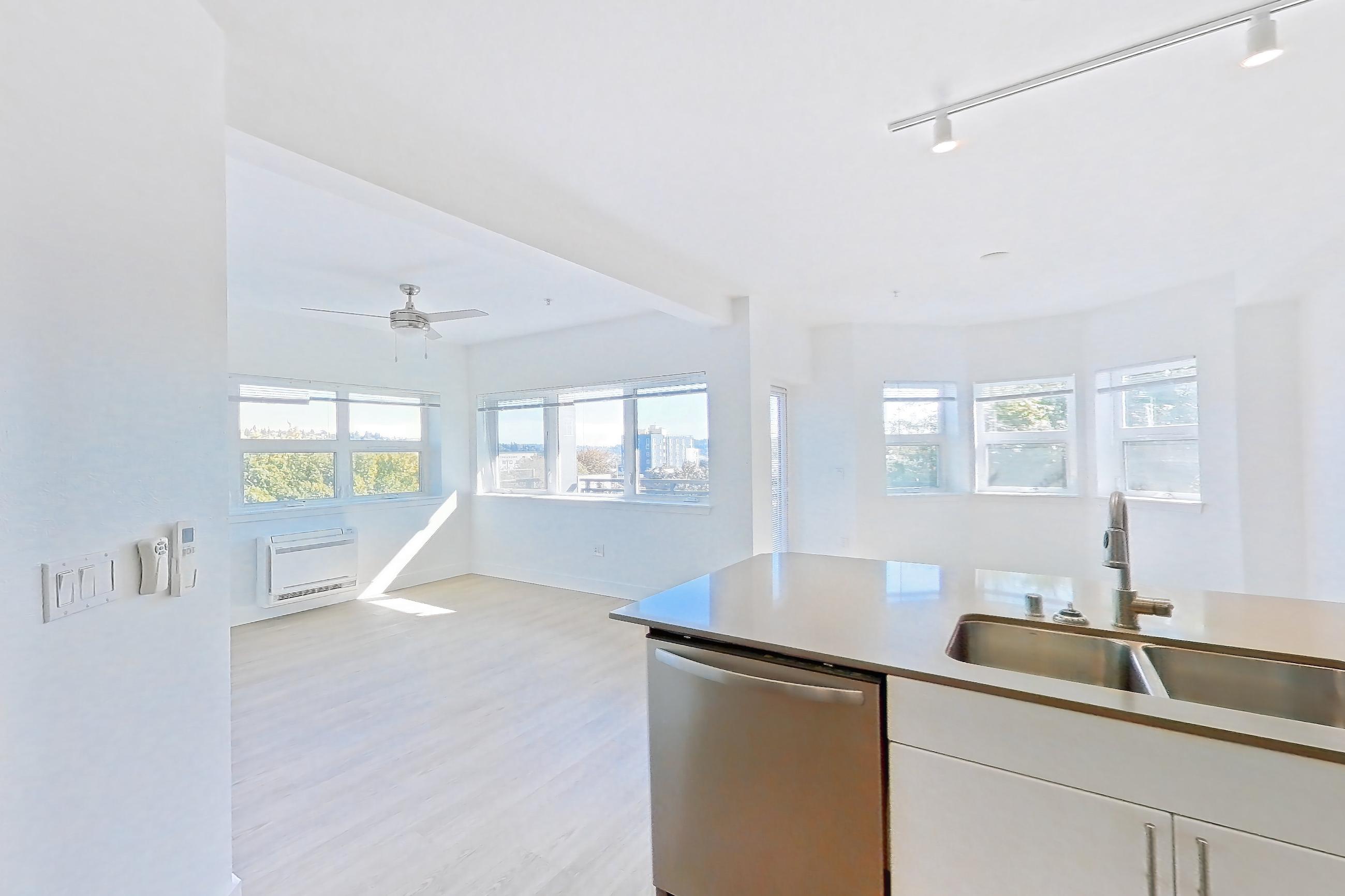 Kitchen with dishwasher, electric range, light countertops, light stone countertops, light wood-finish flooring, microwave, oven/range, refrigerator, and stainless steel appliances, Unit 307 at The Waymark
