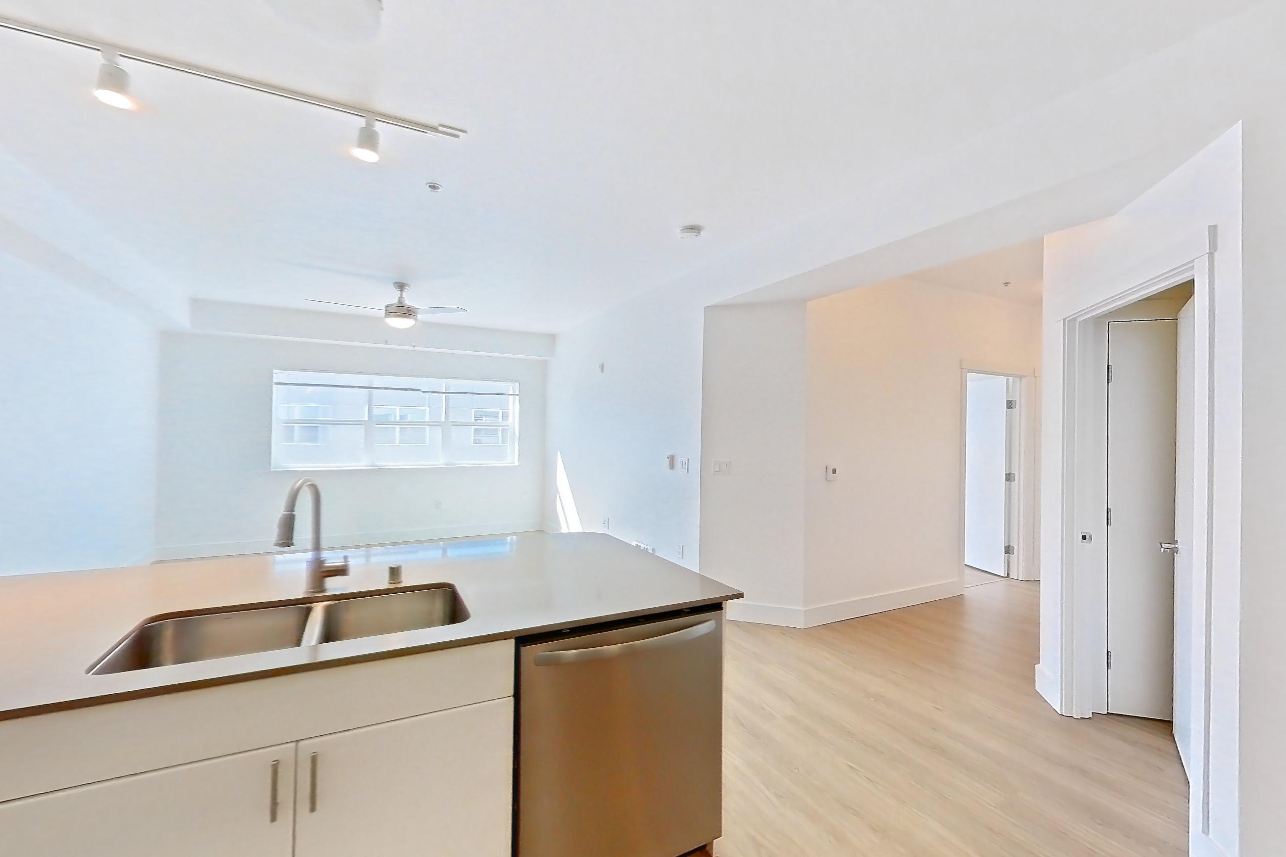 Kitchen with dishwasher, electric range, light countertops, light wood-finish flooring, oven/range, refrigerator, and stainless steel appliances, Unit 801 at The Waymark
