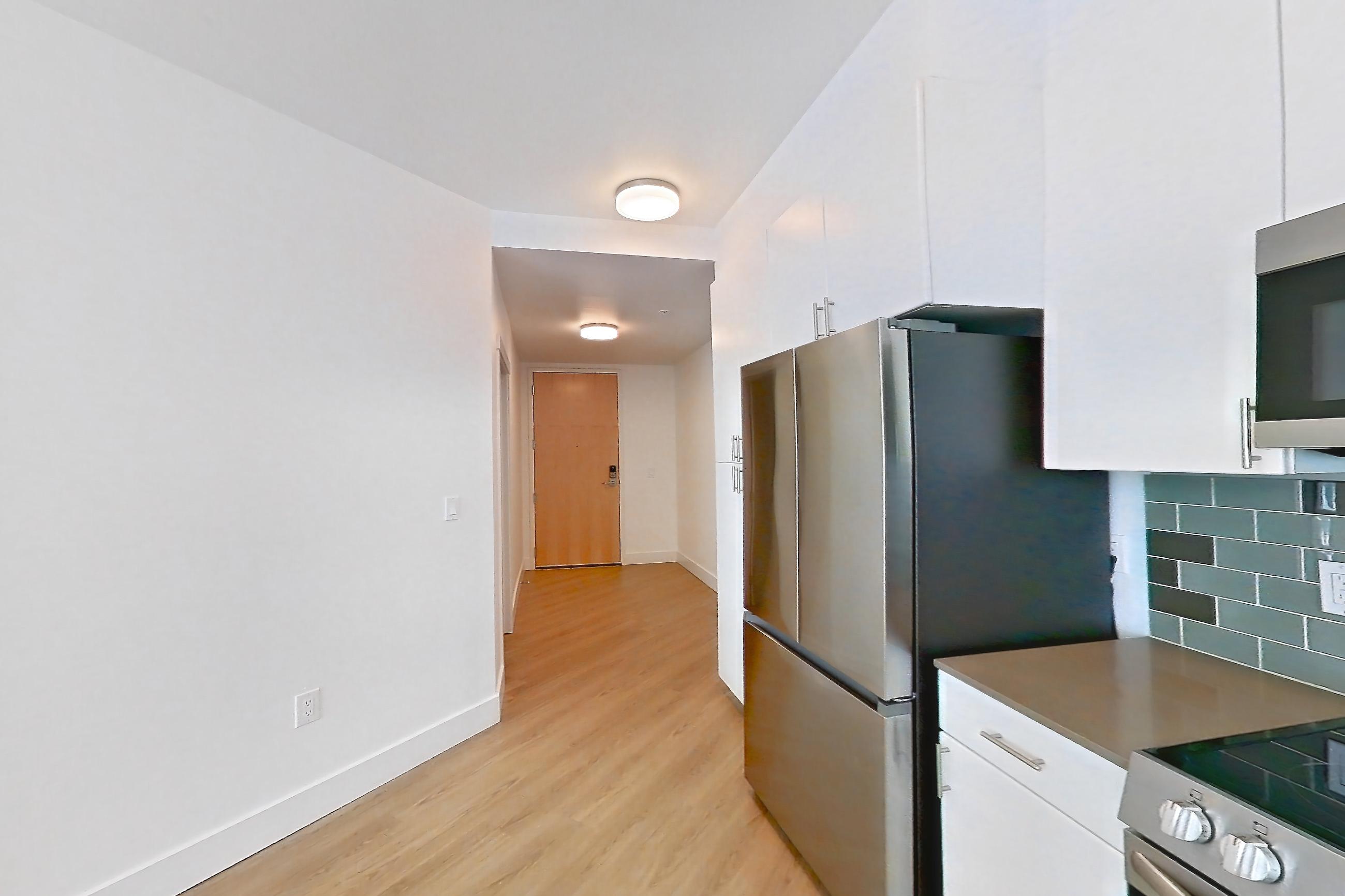 Kitchen with dishwasher, electric range, light countertops, light wood-finish flooring, oven/range, refrigerator, and stainless steel appliances, Unit 801 at The Waymark
