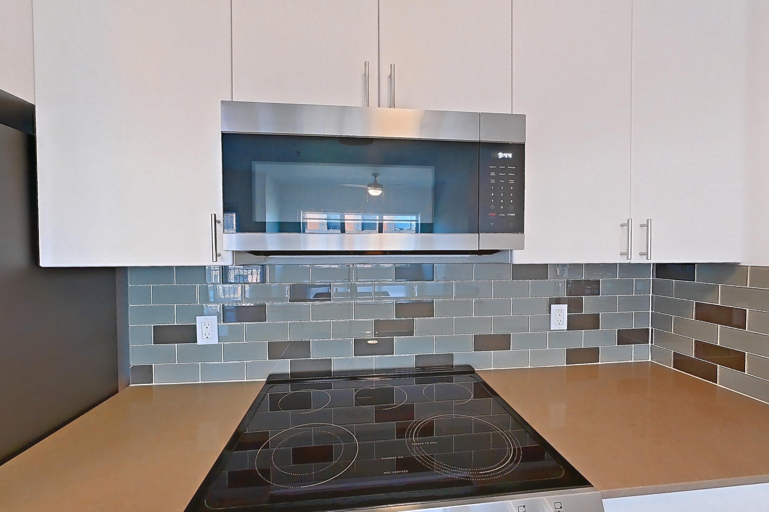 Kitchen with dishwasher, electric range, light countertops, light wood-finish flooring, microwave, oven/range, refrigerator, and stainless steel appliances, Unit 432 at The Waymark