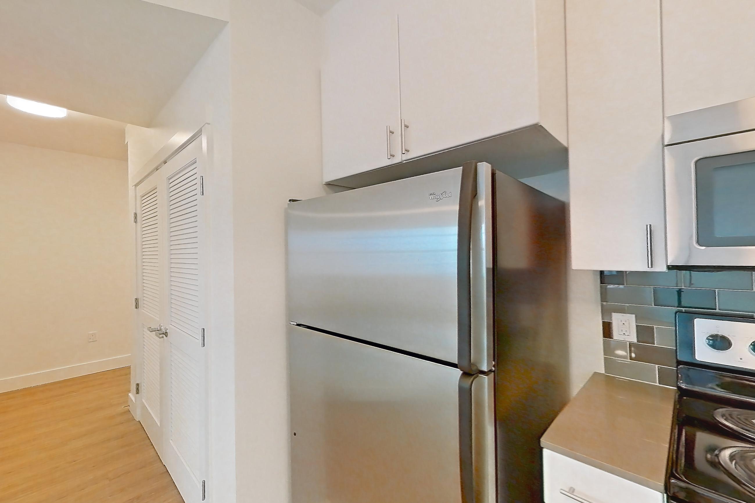 Kitchen with baseboard heating, dishwasher, electric range, light countertops, light wood-finish flooring, microwave, oven/range, refrigerator, and stainless steel appliances, Unit 501 at The Waymark