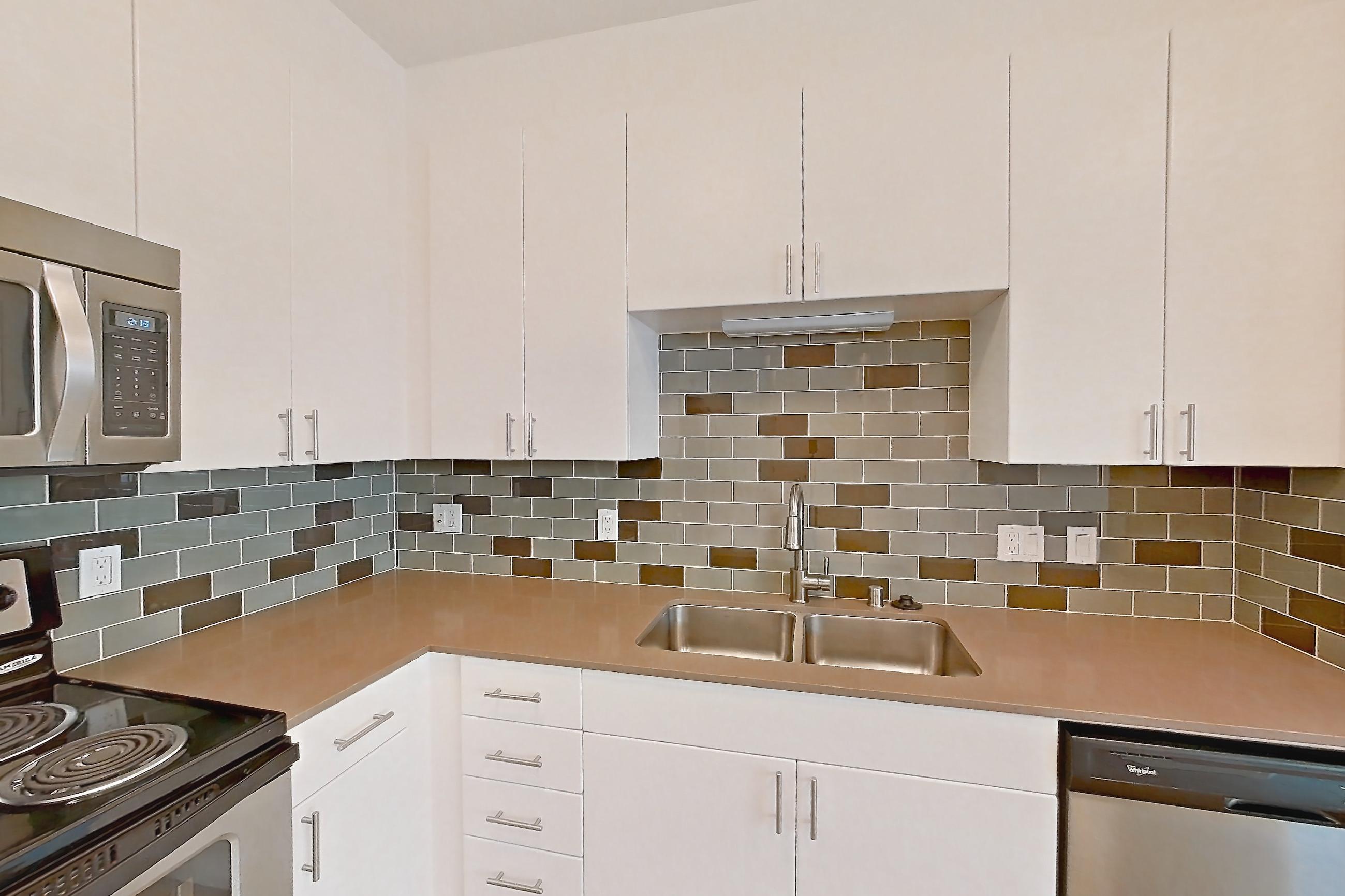 Kitchen with baseboard heating, dishwasher, electric range, light countertops, light wood-finish flooring, microwave, oven/range, refrigerator, and stainless steel appliances, Unit 501 at The Waymark