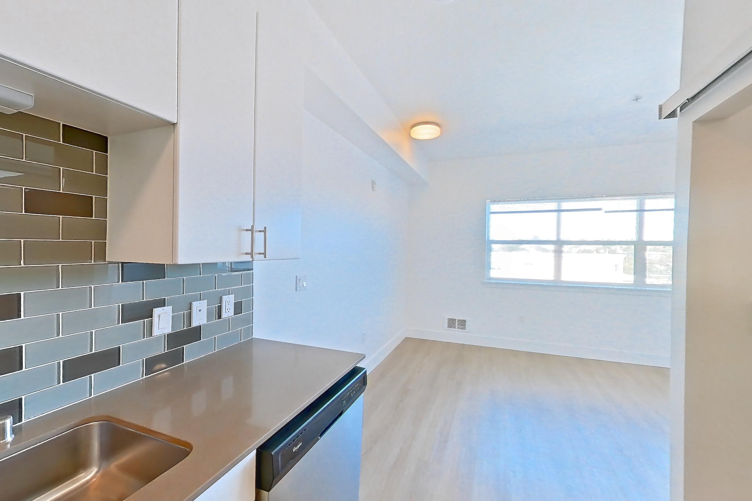 Kitchen with baseboard heating, black appliances, dishwasher, electric range, light countertops, light wood-finish flooring, oven/range, refrigerator, and stainless steel appliances, Unit 825 at The Waymark