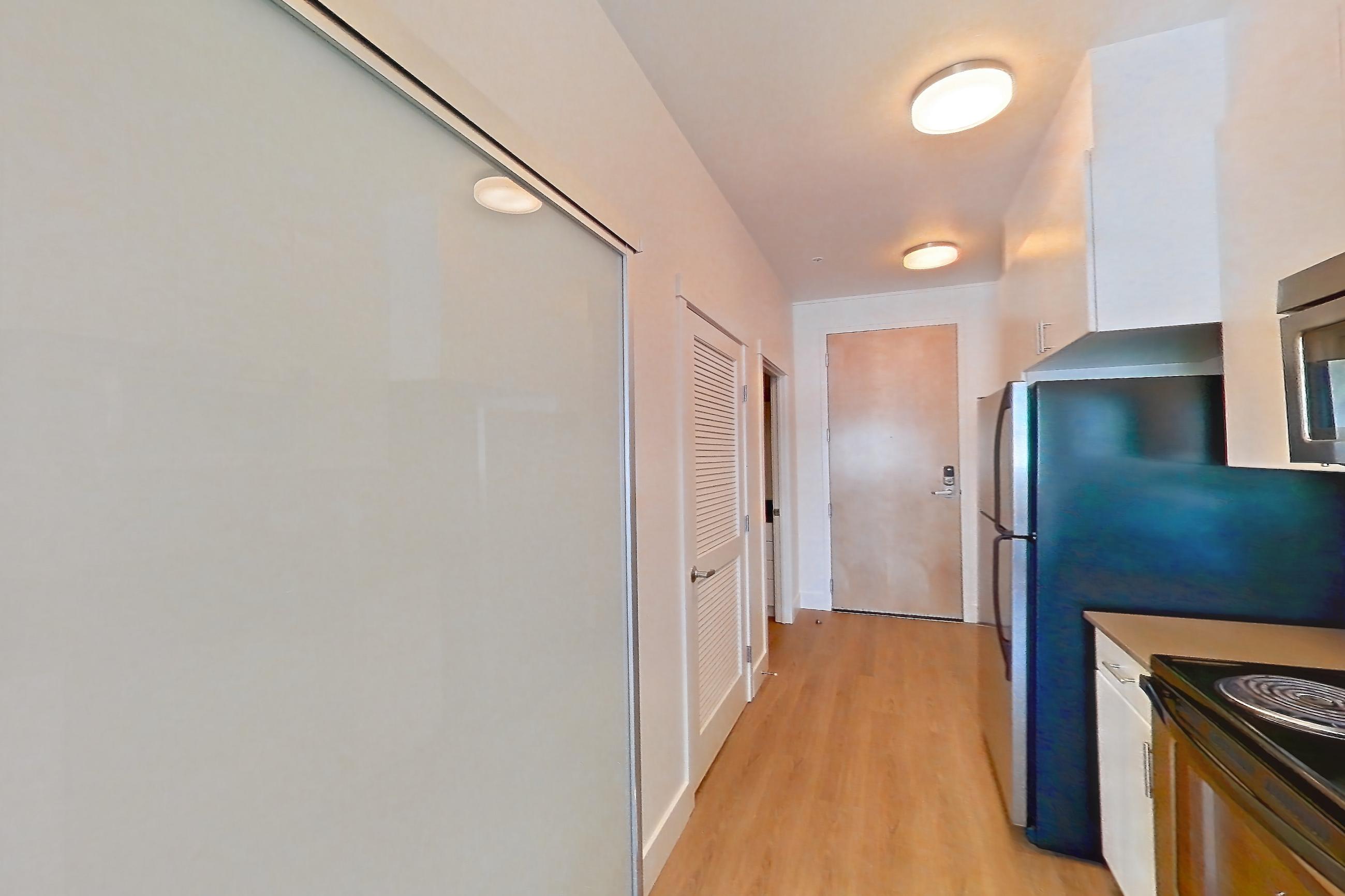 Kitchen with baseboard heating, black appliances, dishwasher, electric range, light countertops, light wood-finish flooring, oven/range, refrigerator, and stainless steel appliances, Unit 825 at The Waymark