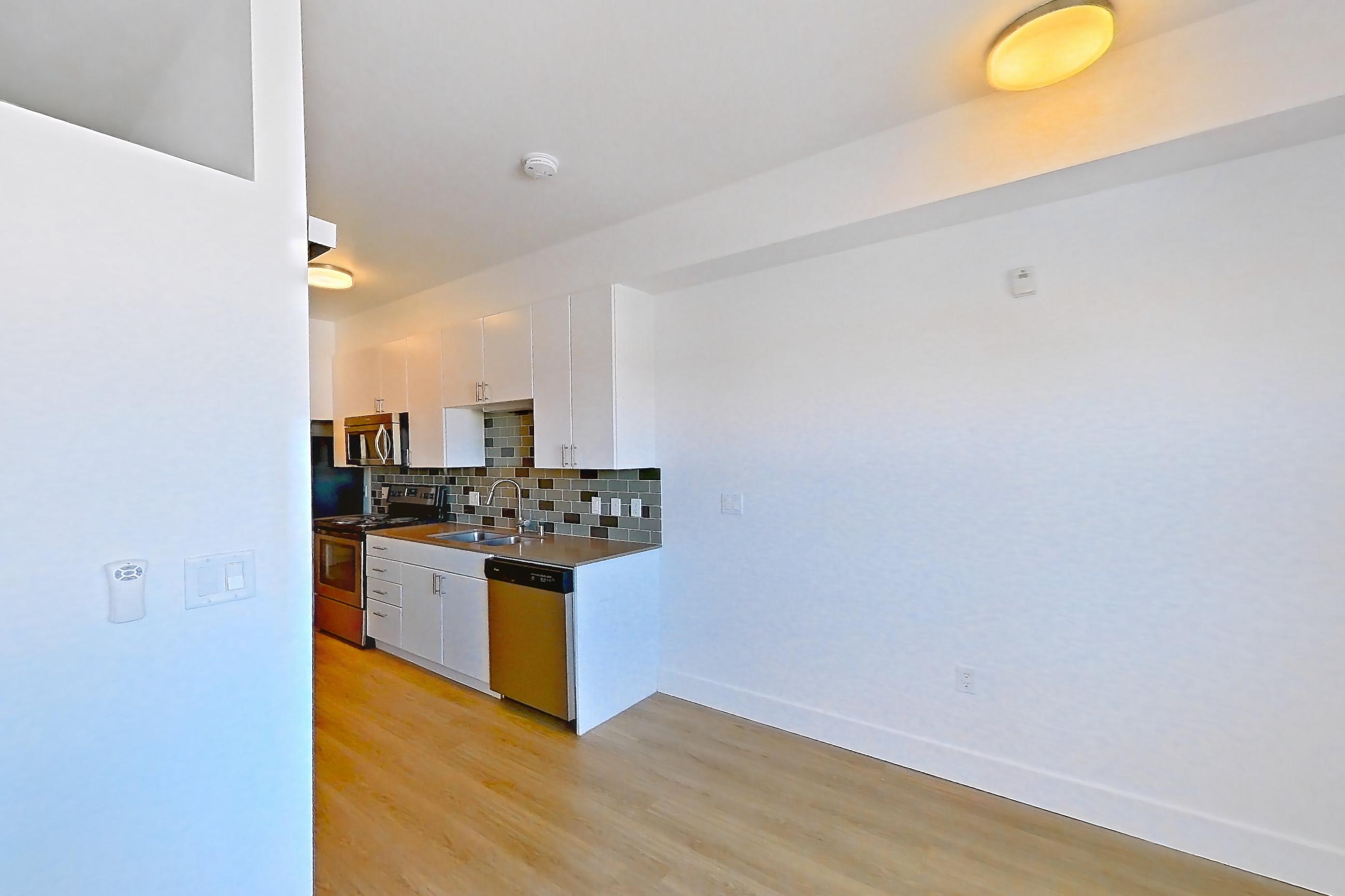 Living room with dishwasher, light wood-finish flooring, and stainless steel appliances, Unit 825 at The Waymark
