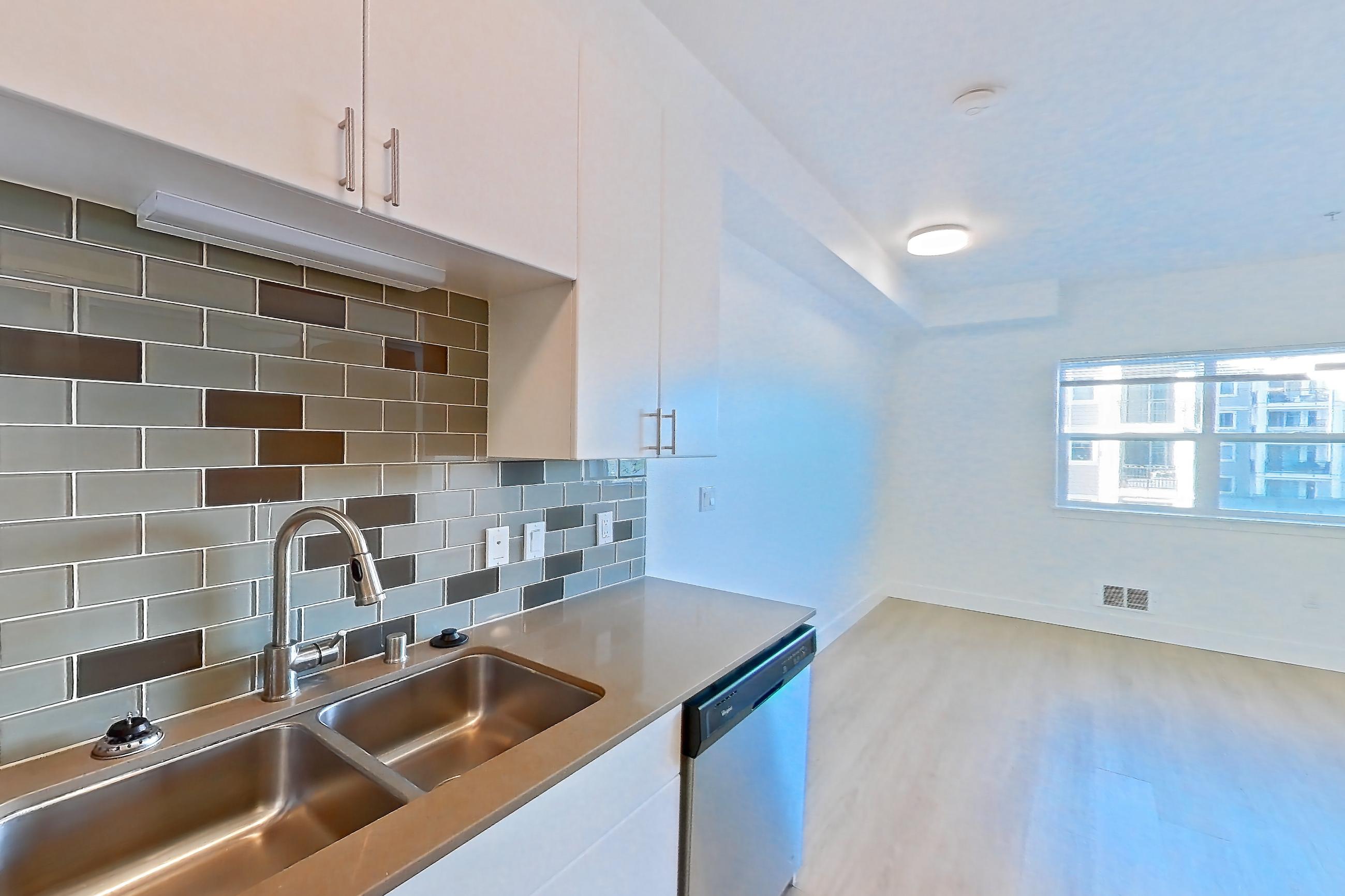 Kitchen with black appliances, dark countertops, dishwasher, electric range, light countertops, light wood-finish flooring, microwave, oven/range, refrigerator, and stainless steel appliances, Apartment 423 at The Waymark