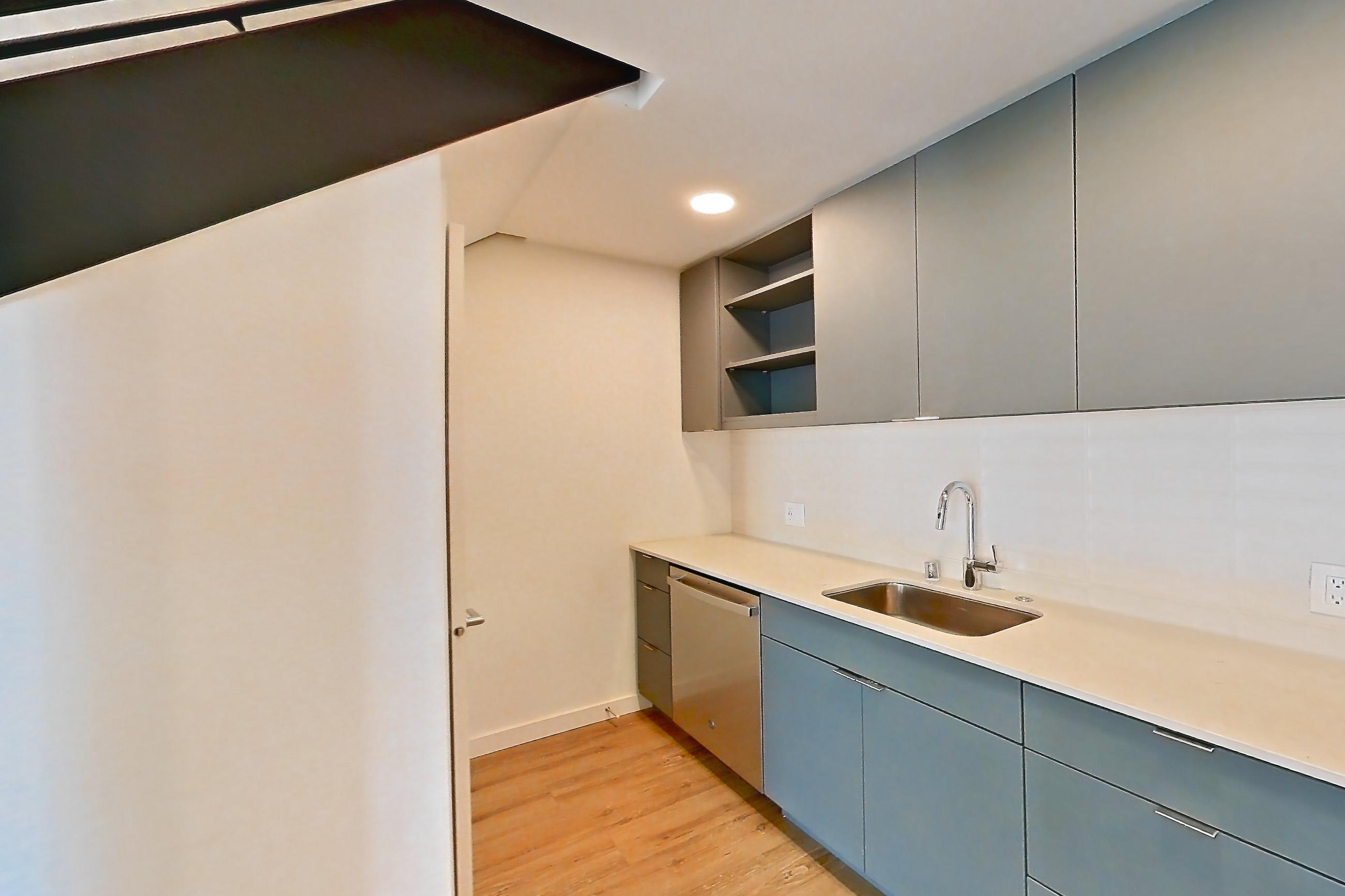 Kitchen with dishwasher, electric range, light countertops, light stone countertops, light wood-finish flooring, microwave, oven/range, refrigerator, and stainless steel appliances, Unit 130 at Arlo