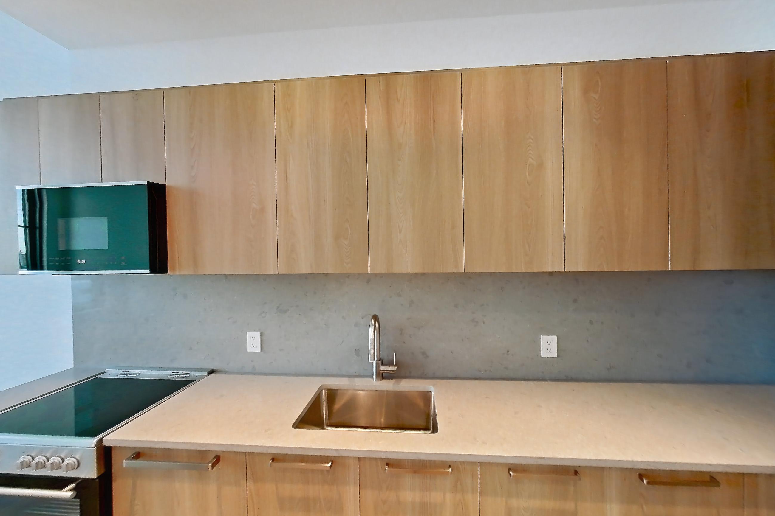 Kitchen with electric range, light countertops, light stone countertops, light wood-finish flooring, oven/range, refrigerator, and stainless steel appliances, Unit 0502 at Hearthstone